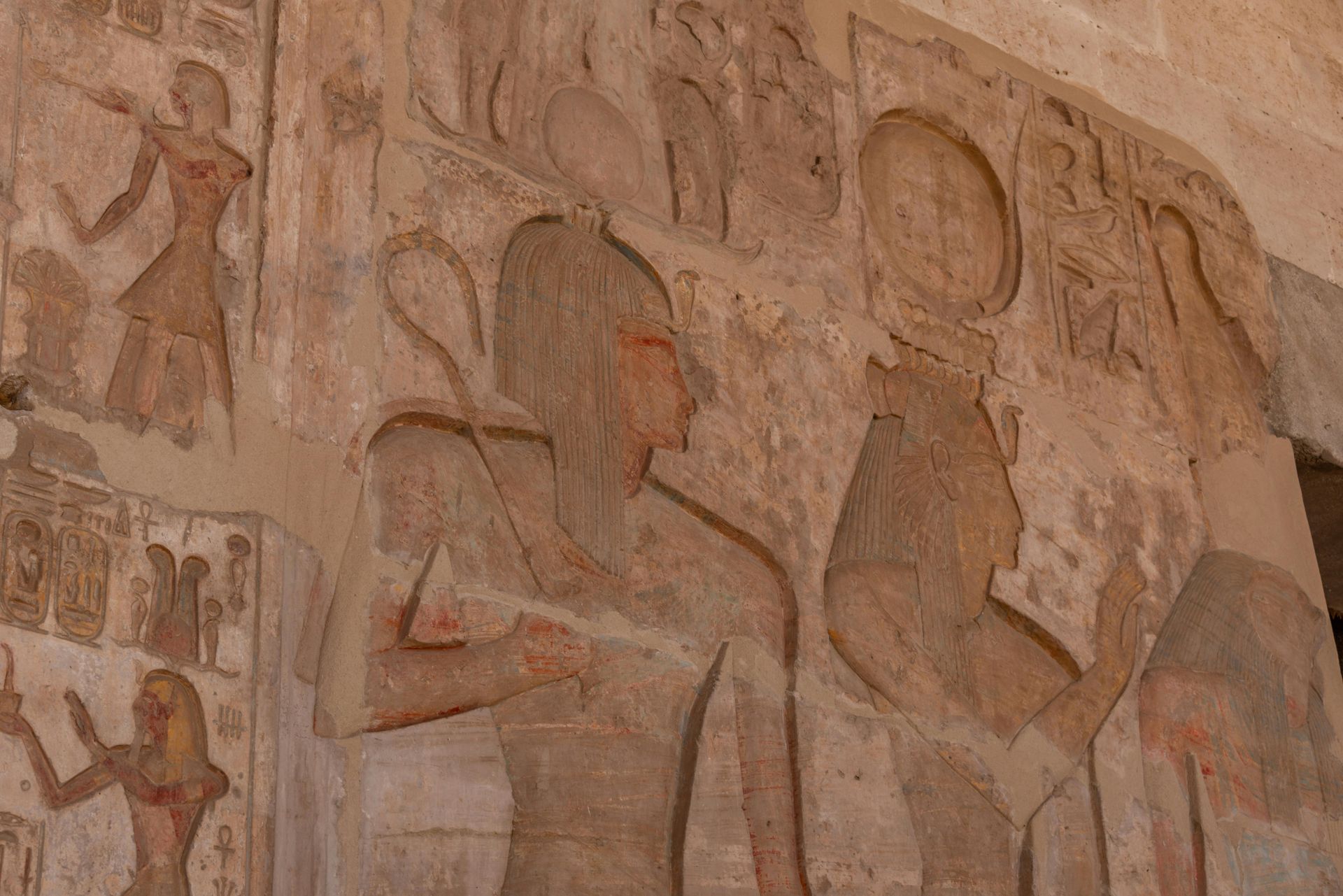 A stone carving of a man and a woman on a wall in Egypt.