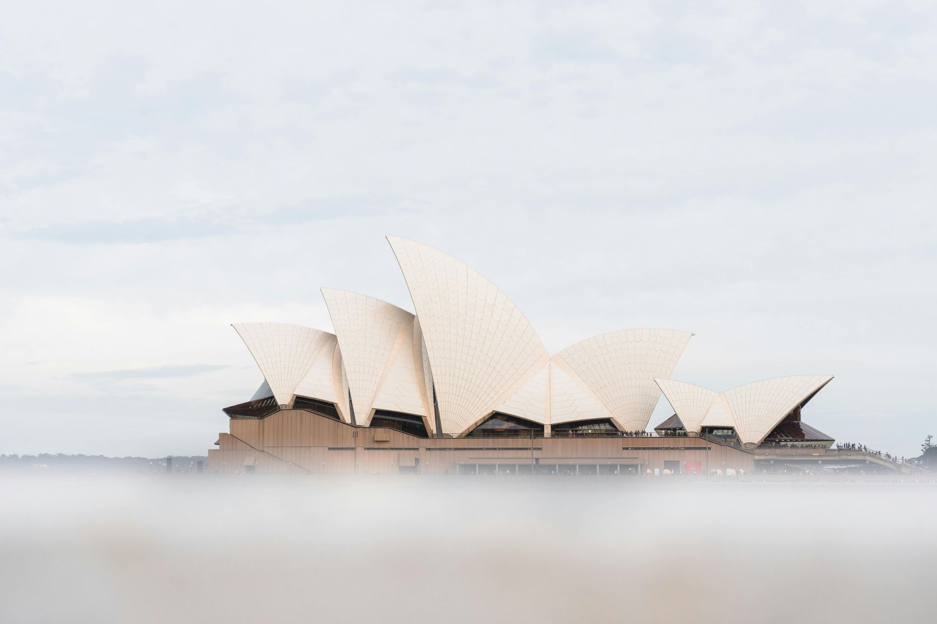 The sydney opera house is covered in fog on a cloudy day in Australia.