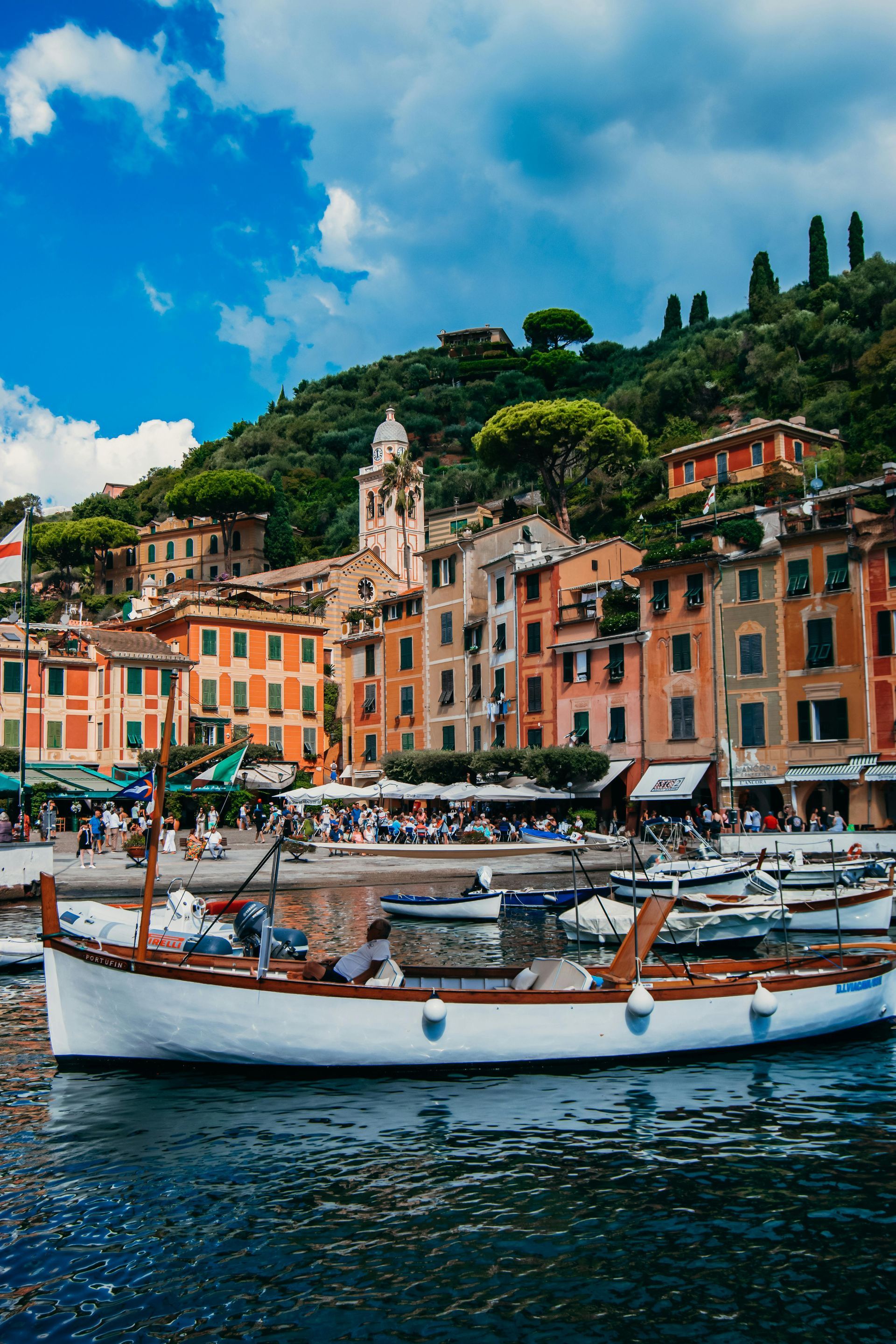 A boat is docked in a harbor with buildings in the background in Portofino, Italy.