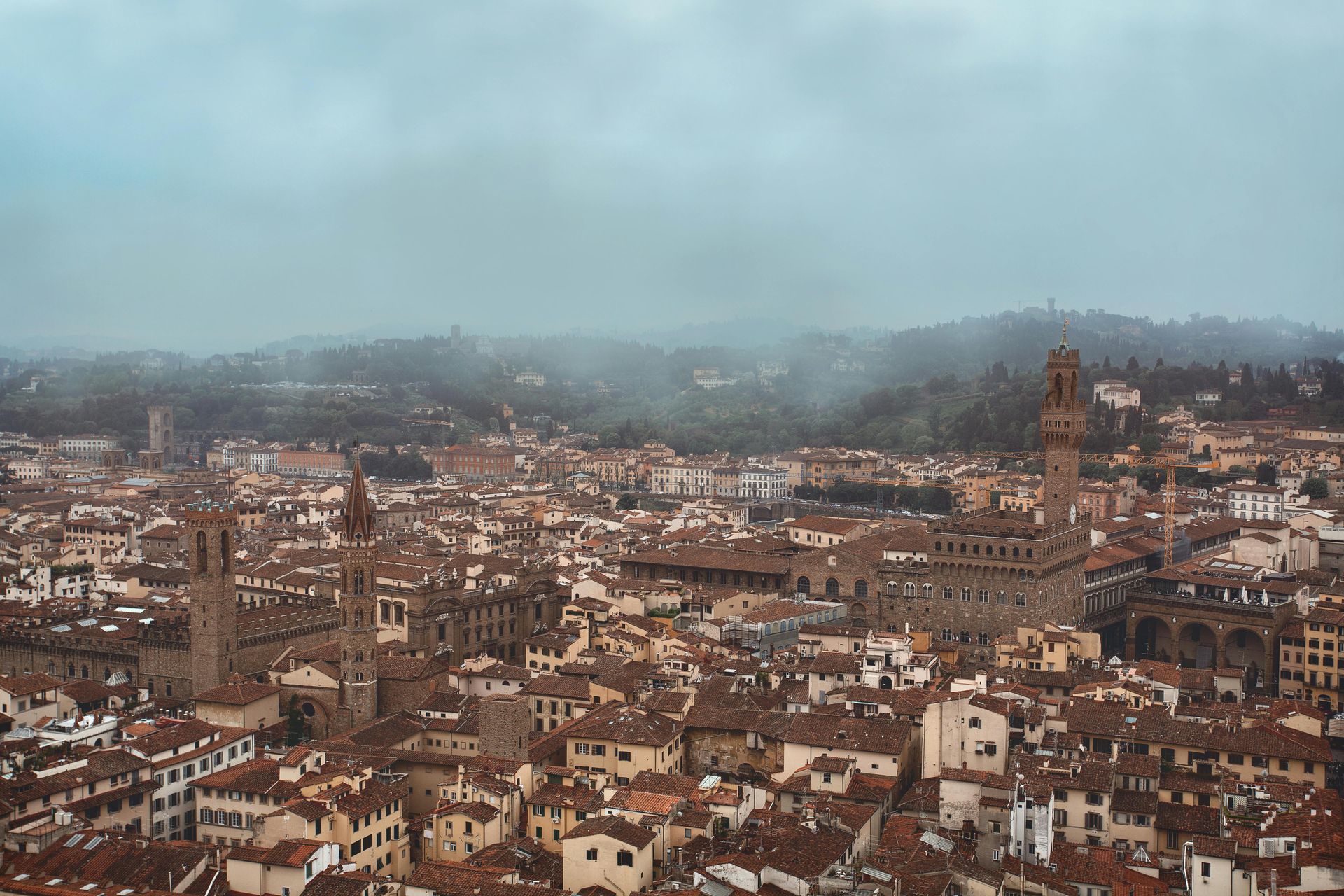 An aerial view of Florence, Italy with a cloudy sky in the background.