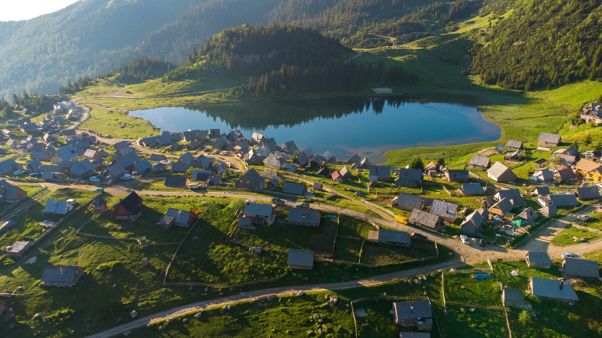 An aerial view of a small village surrounded by mountains and Prokoško Lake in Bosnia and Herzegovina.