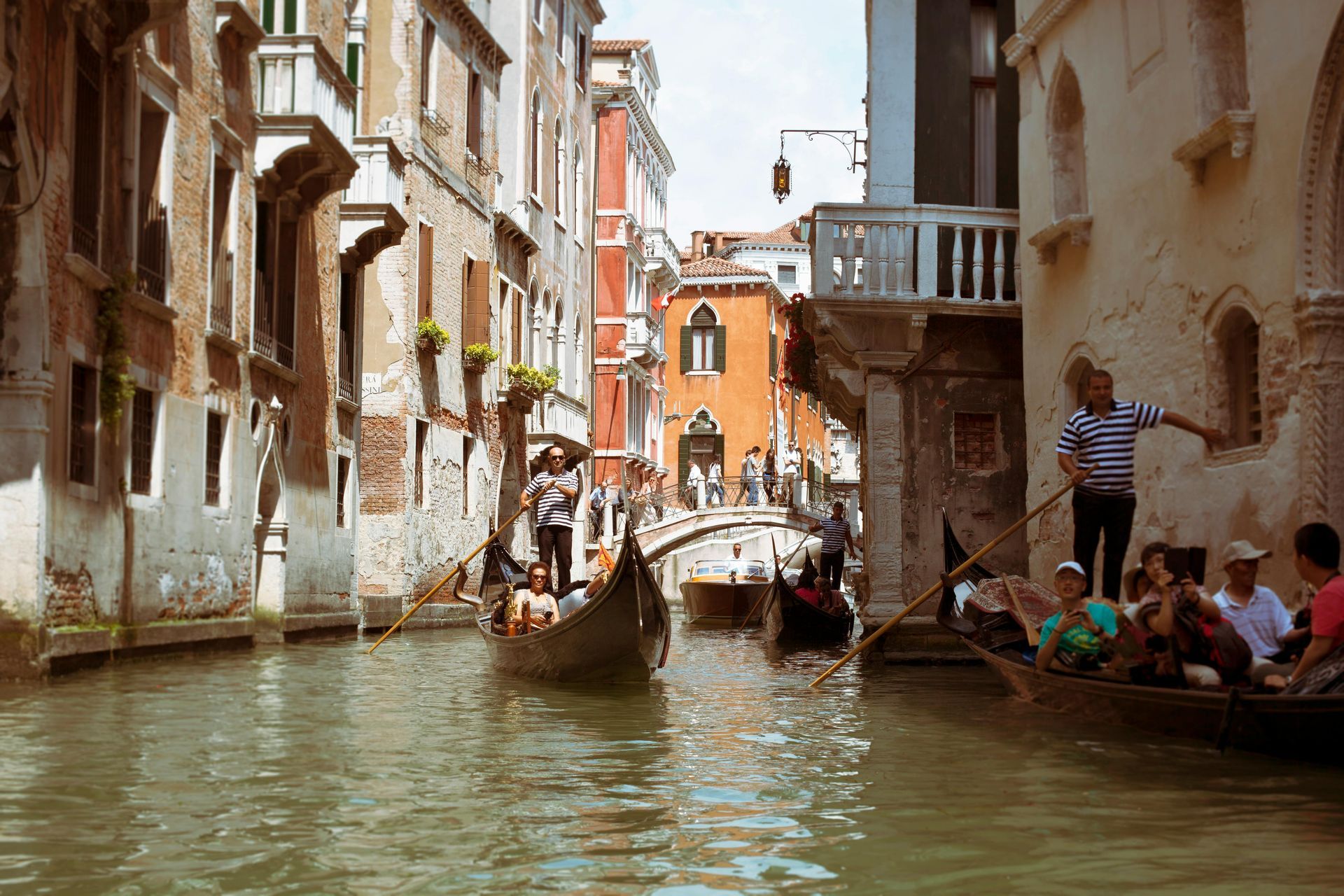 A group of people are riding a gondola down a canal in venice.