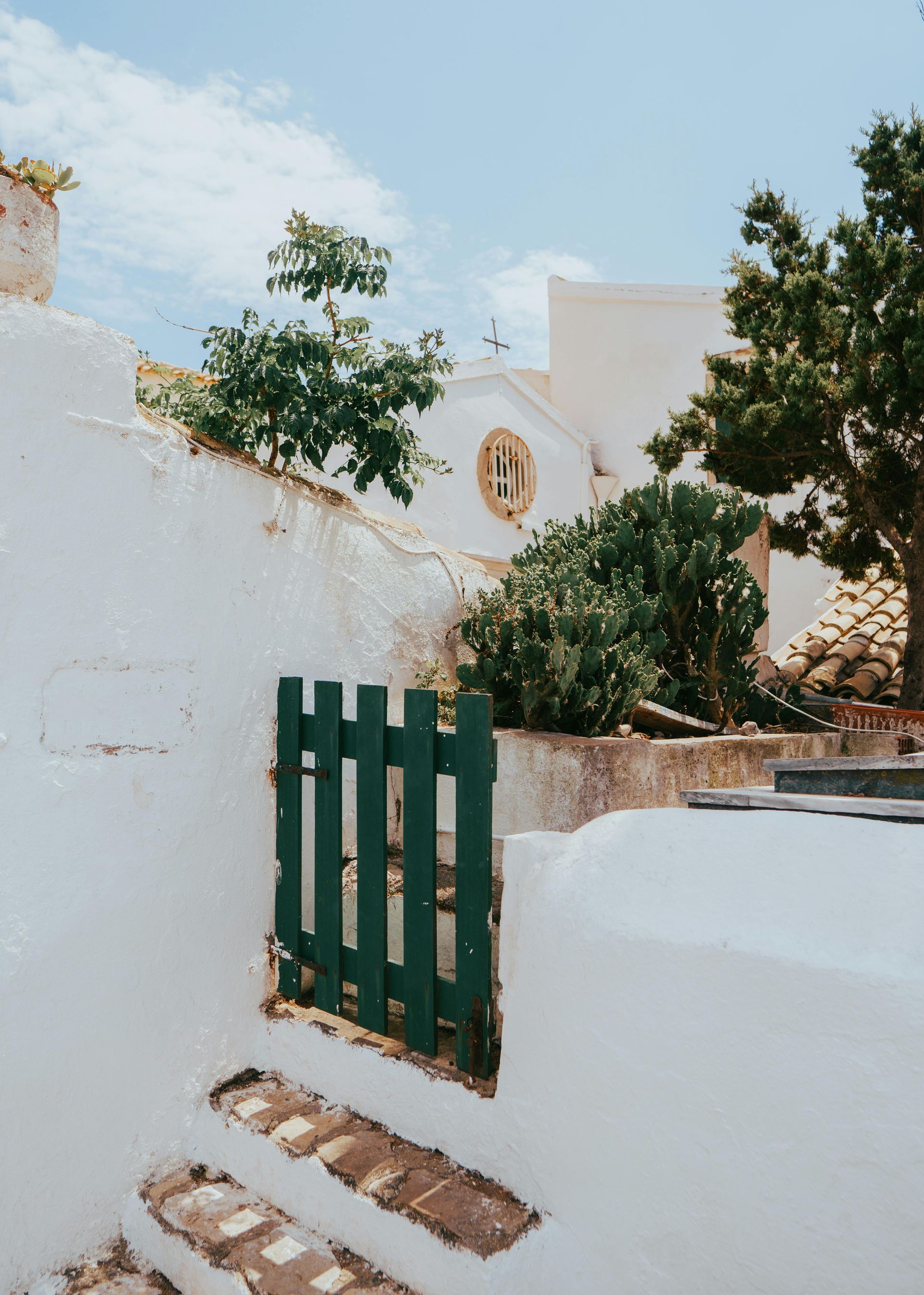 A white building with a green gate in front of it in Corfu, Greece.