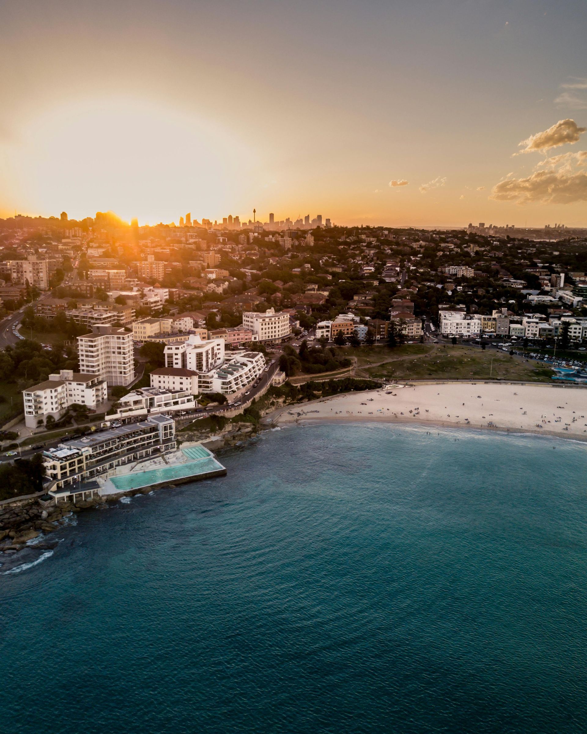 An aerial view of a city and a beach at sunset in Australia.