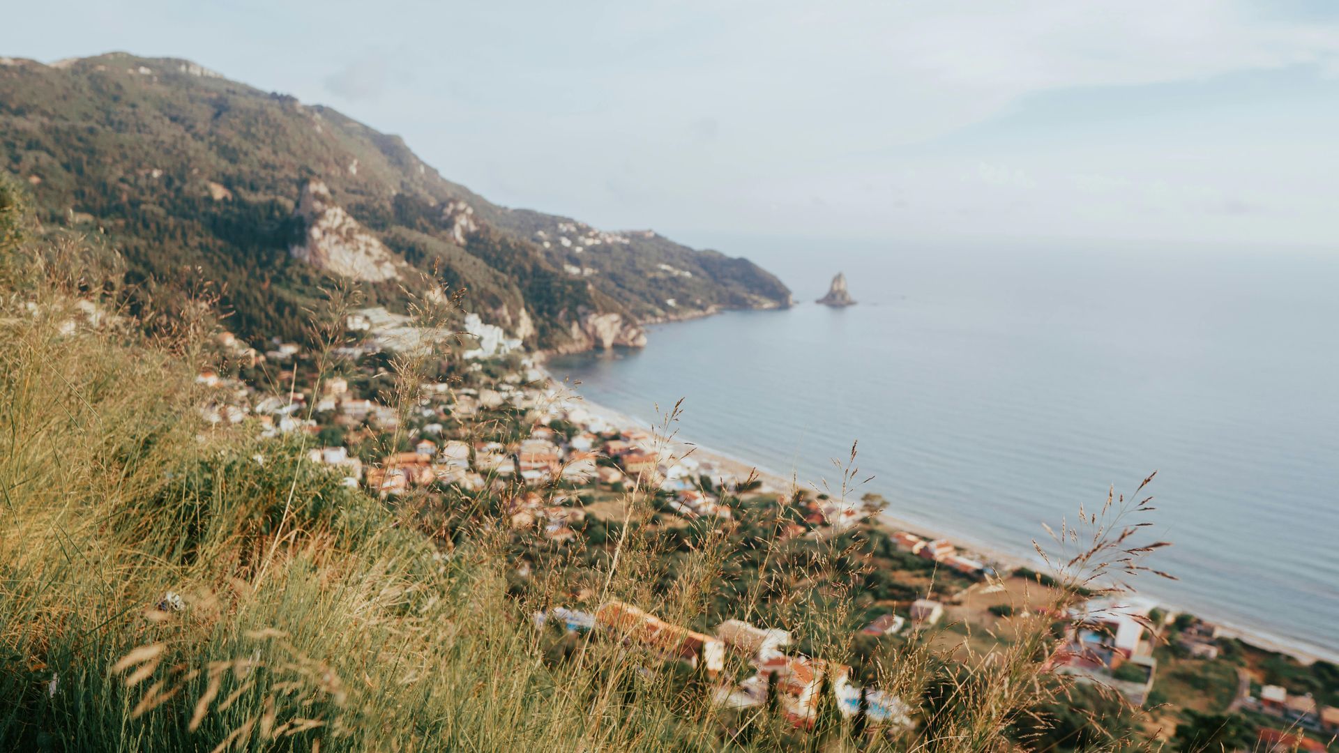 A view of a beach from a hill overlooking the ocean in Corfu, Greece.