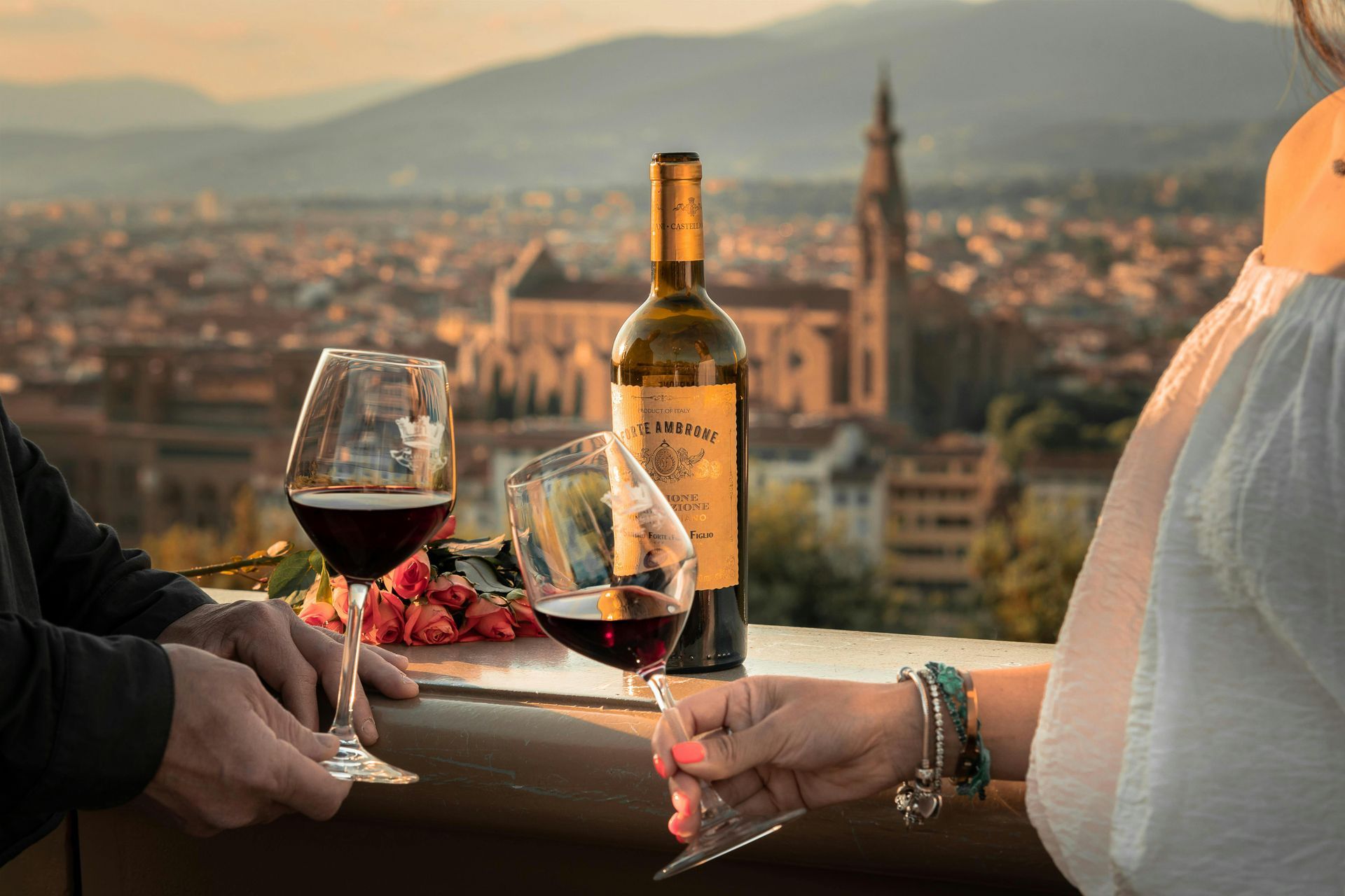 A man and a woman are sitting at a table with wine glasses and a bottle of wine in Tuscany, Italy.