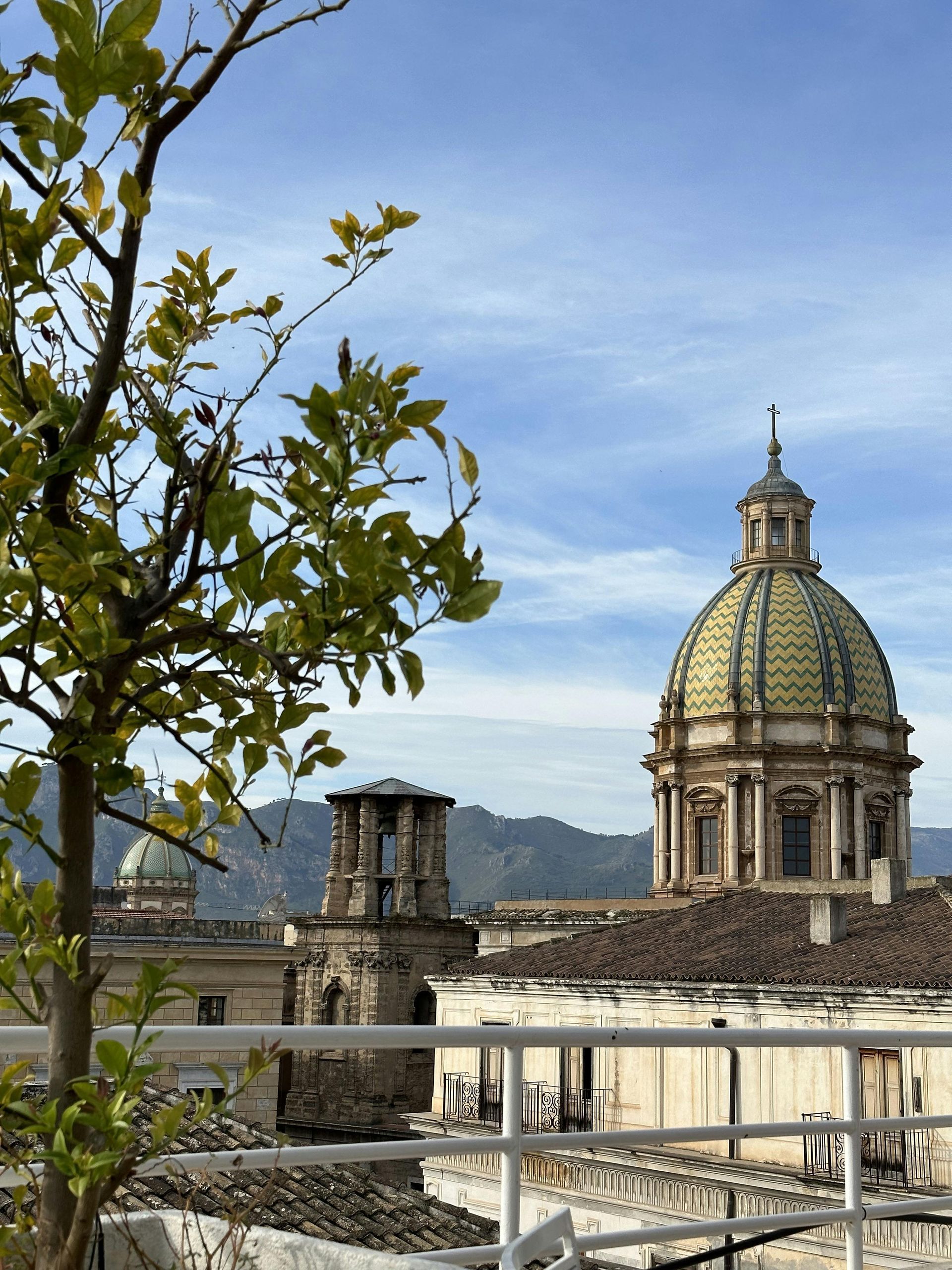 A dome on top of a building with mountains in the background in Sicily Italy.