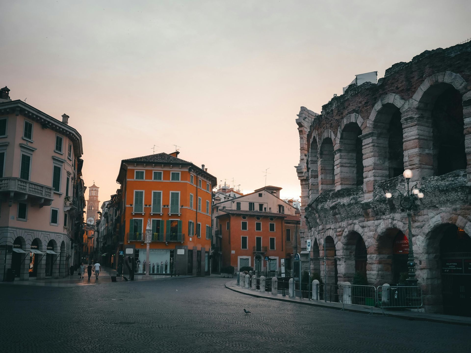 A city street with buildings and arches in the background in Verona, Italy.