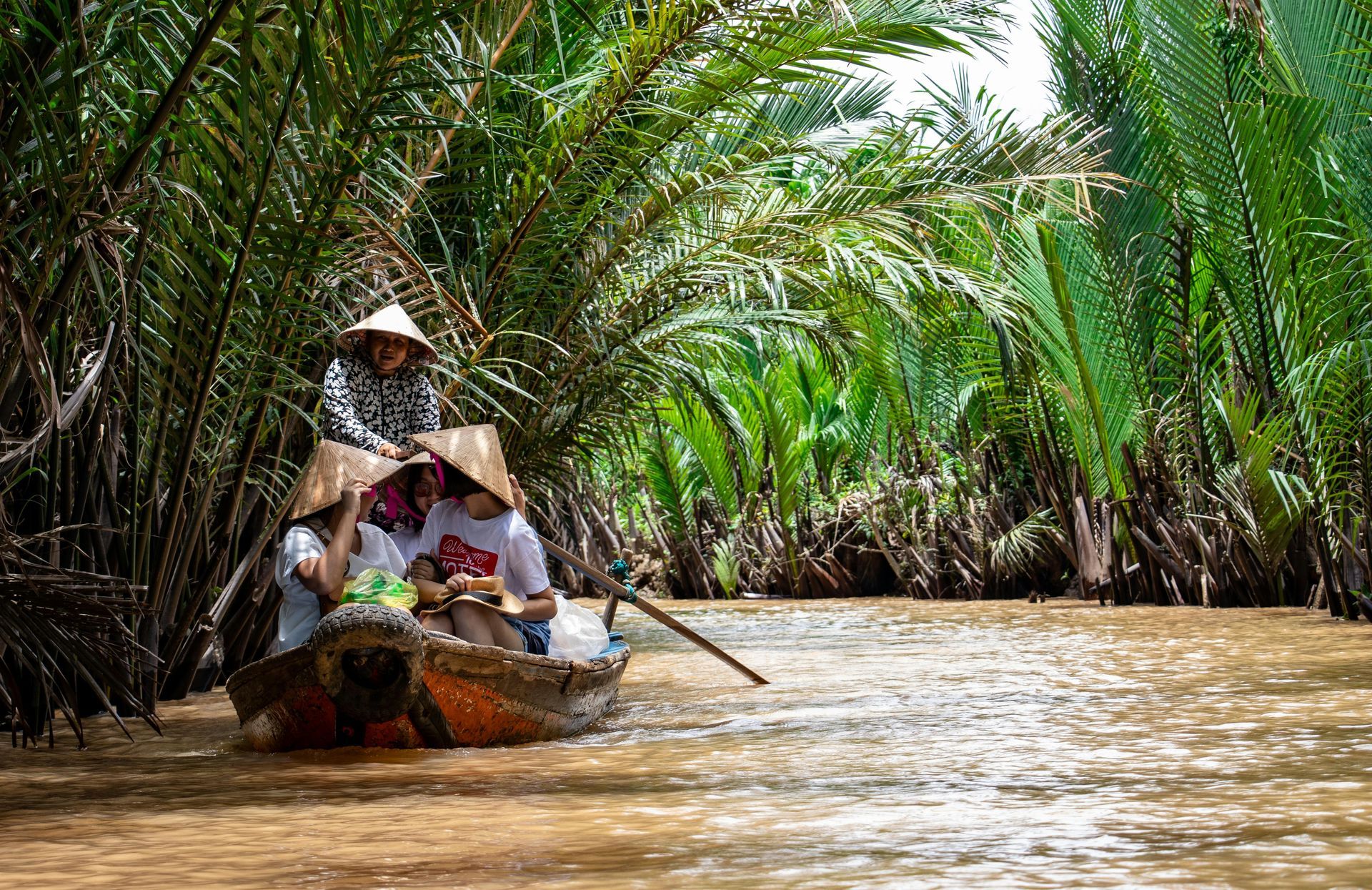 A group of people are rowing a boat down a river in Vietnam.