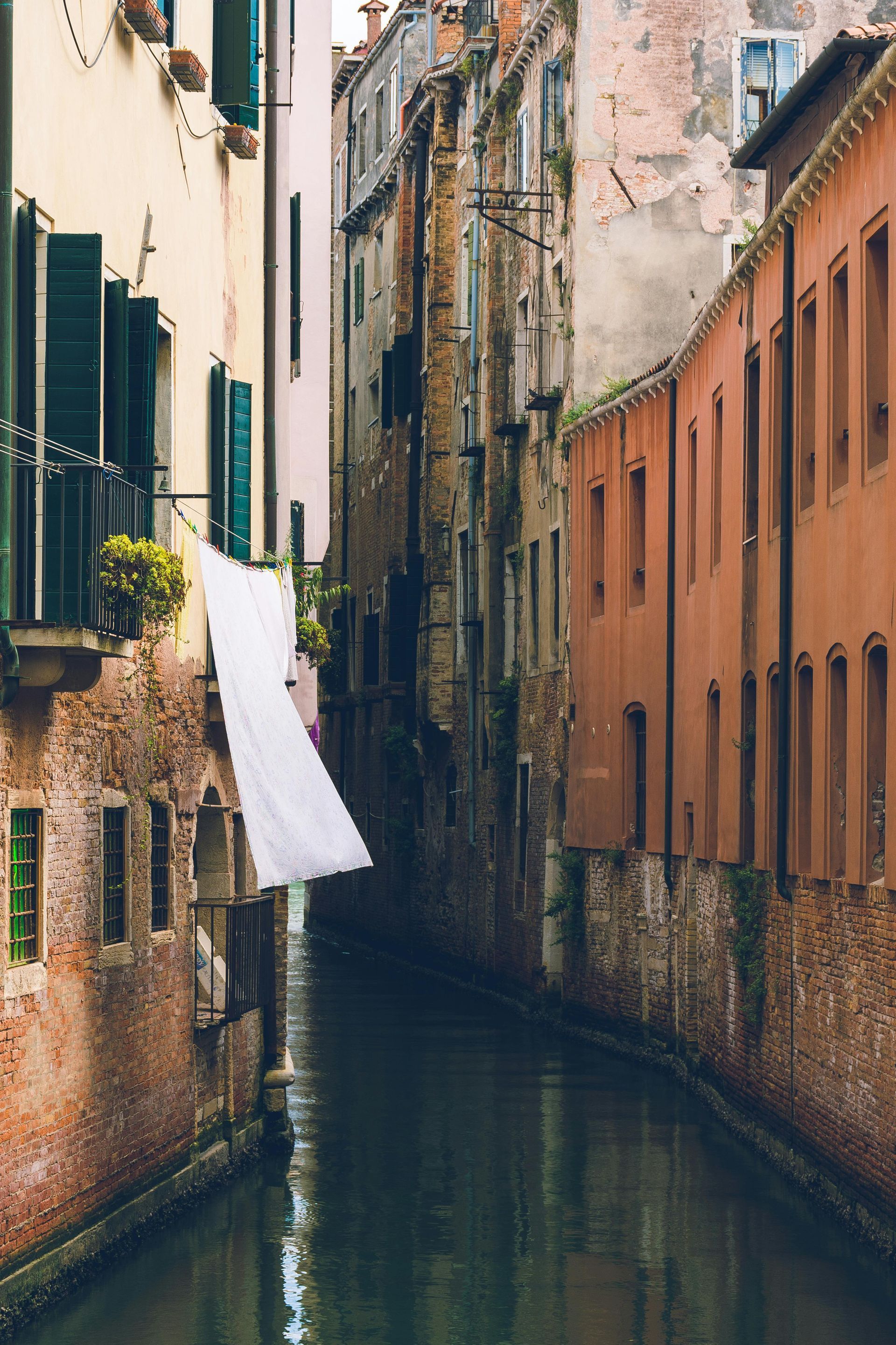 A white cloth is hanging on a clothes line next to a canal in Venice, Italy.