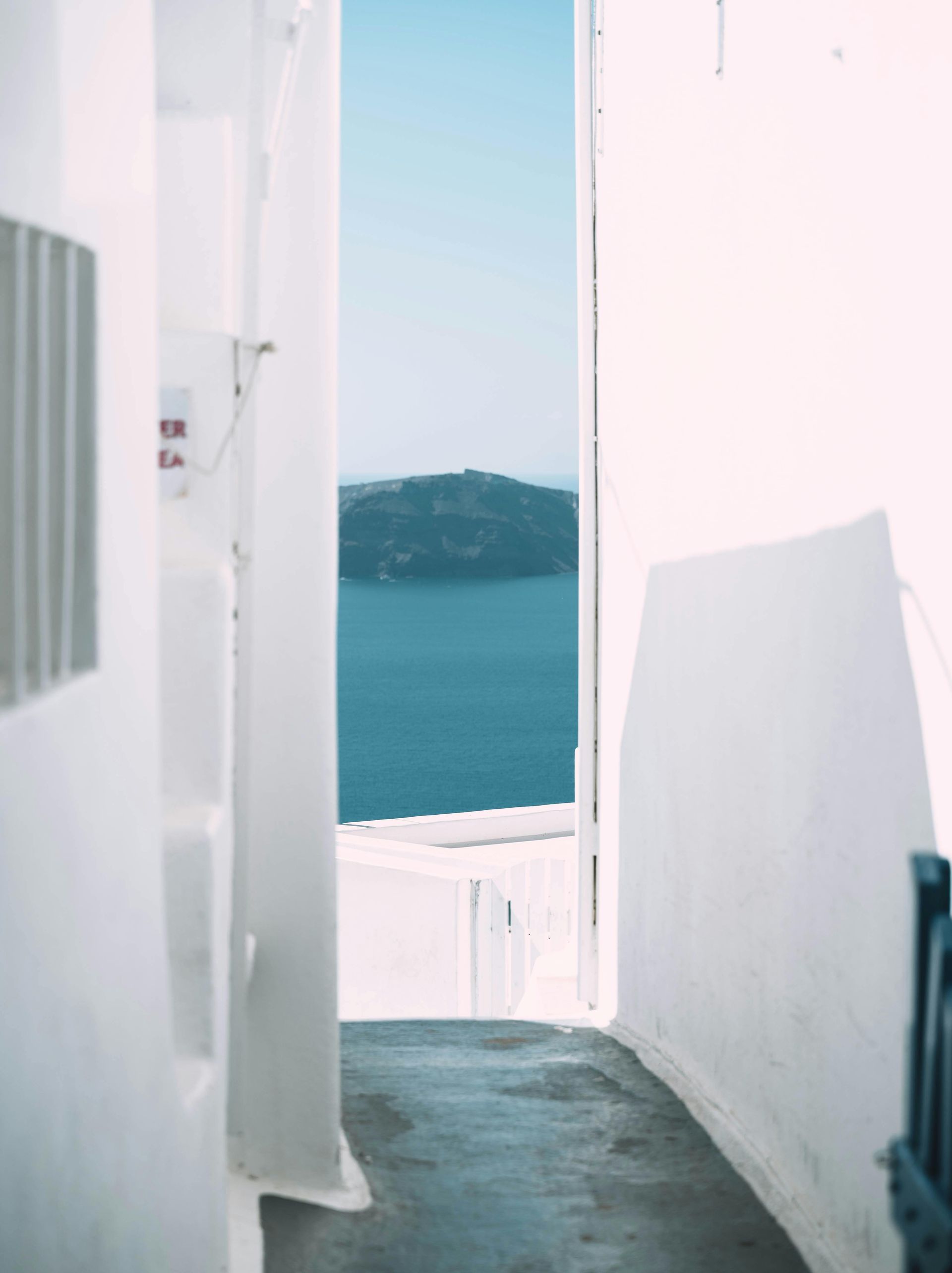 A narrow alleyway with a view of the ocean in Santorini, Greece.