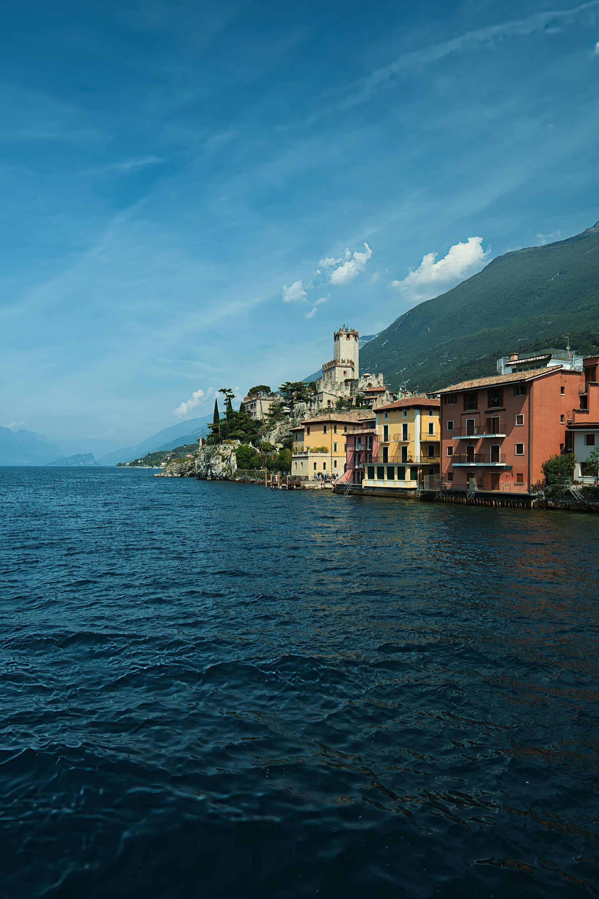 A small town on the shore of Lake Garda with mountains in the background in Italy.