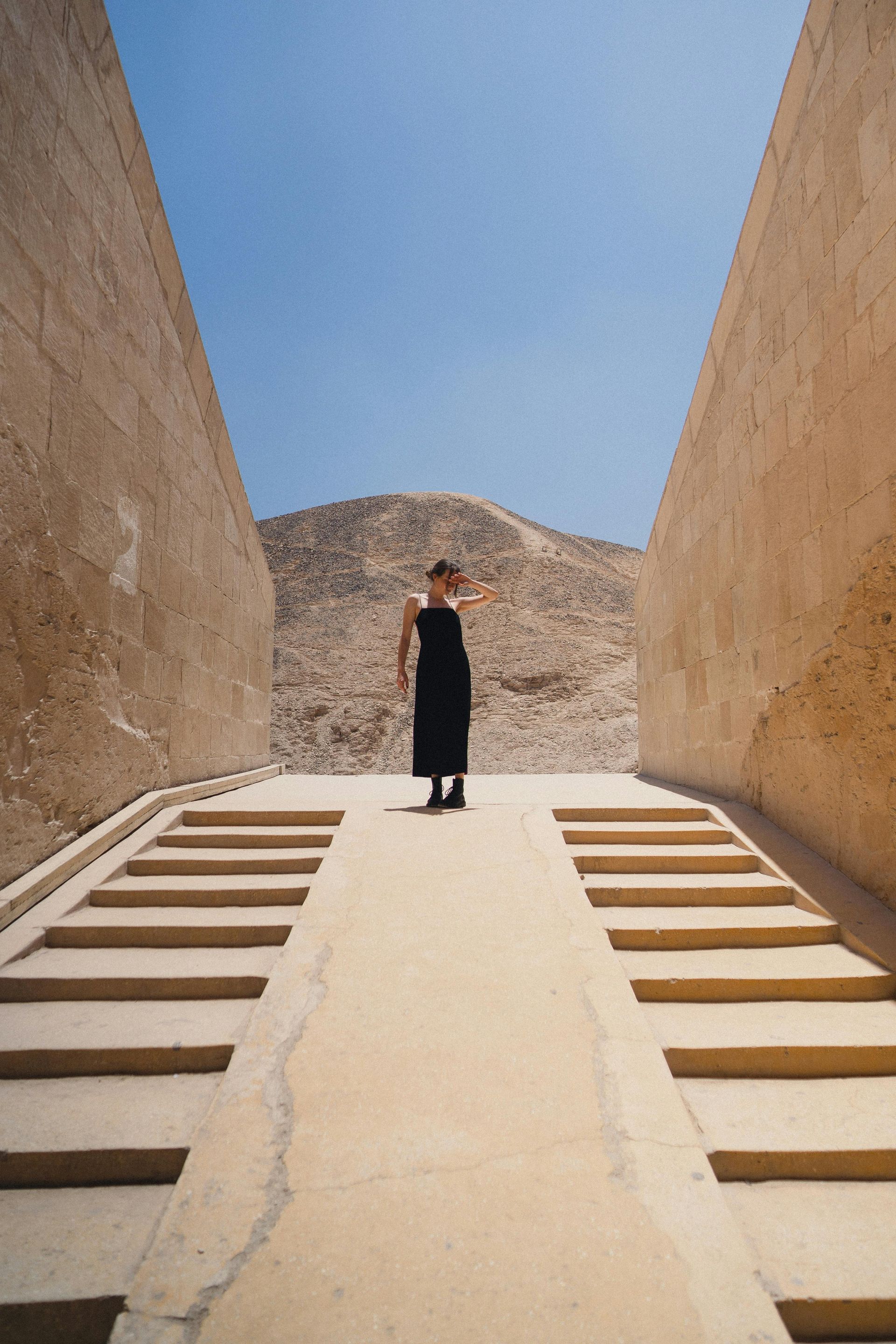 A woman in a black dress is standing on a set of stairs in Egypt.