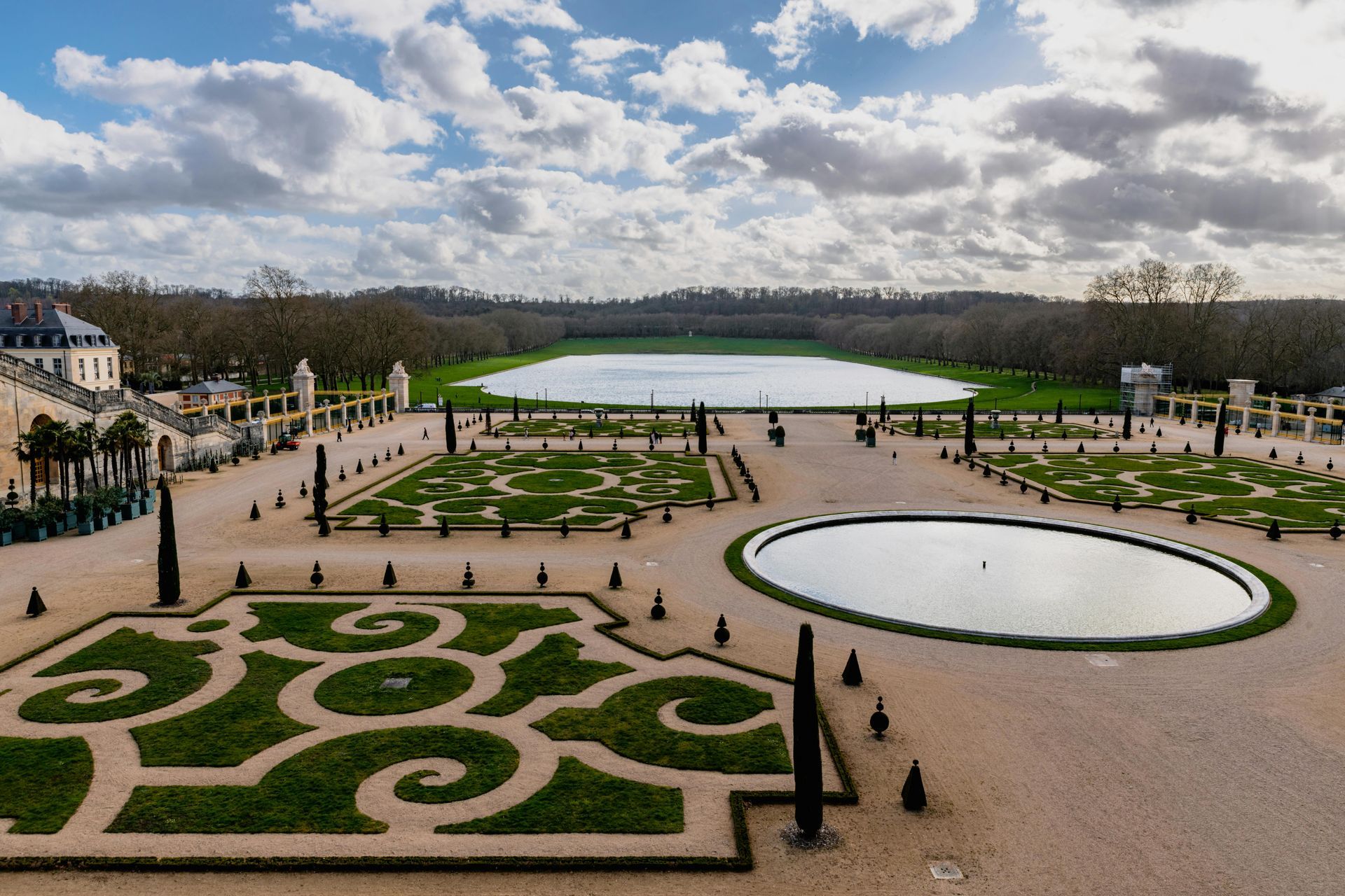 An aerial view of the large garden at the Palace of Versailles with a pond in the middle in France.