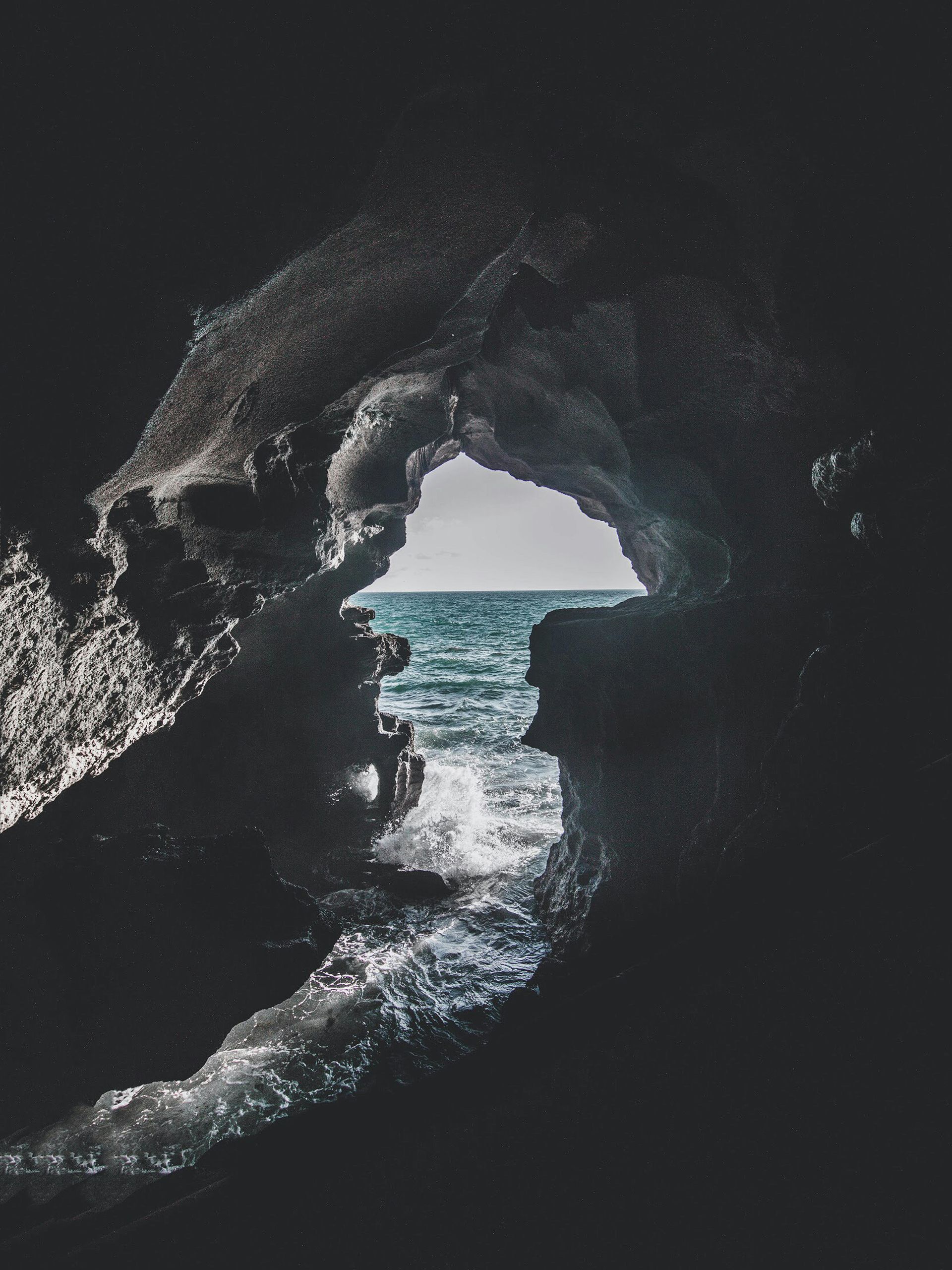 A black and white photo of a cave with a view of the ocean in Morocco.