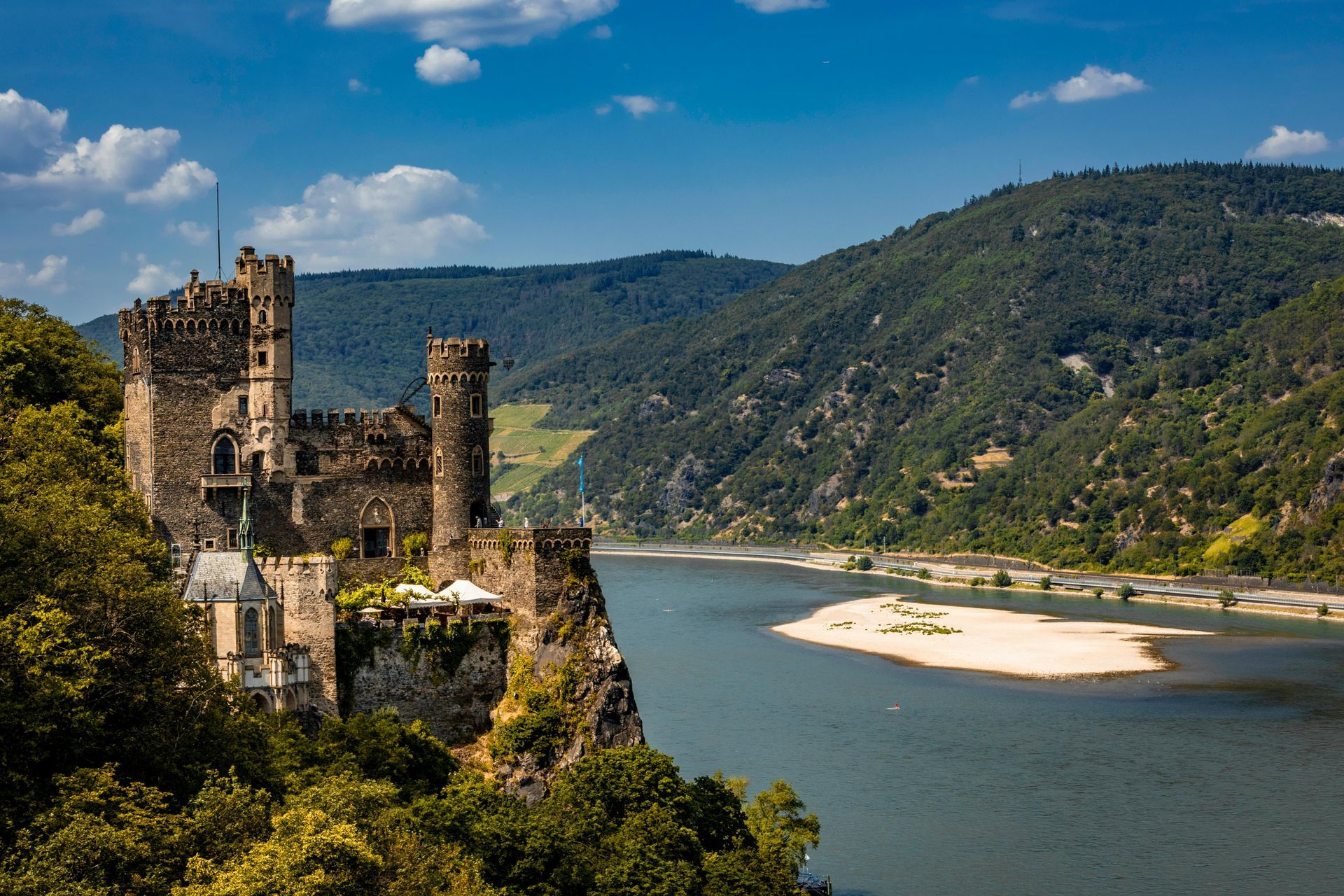 A castle is sitting on top of a cliff overlooking The Rhine River.