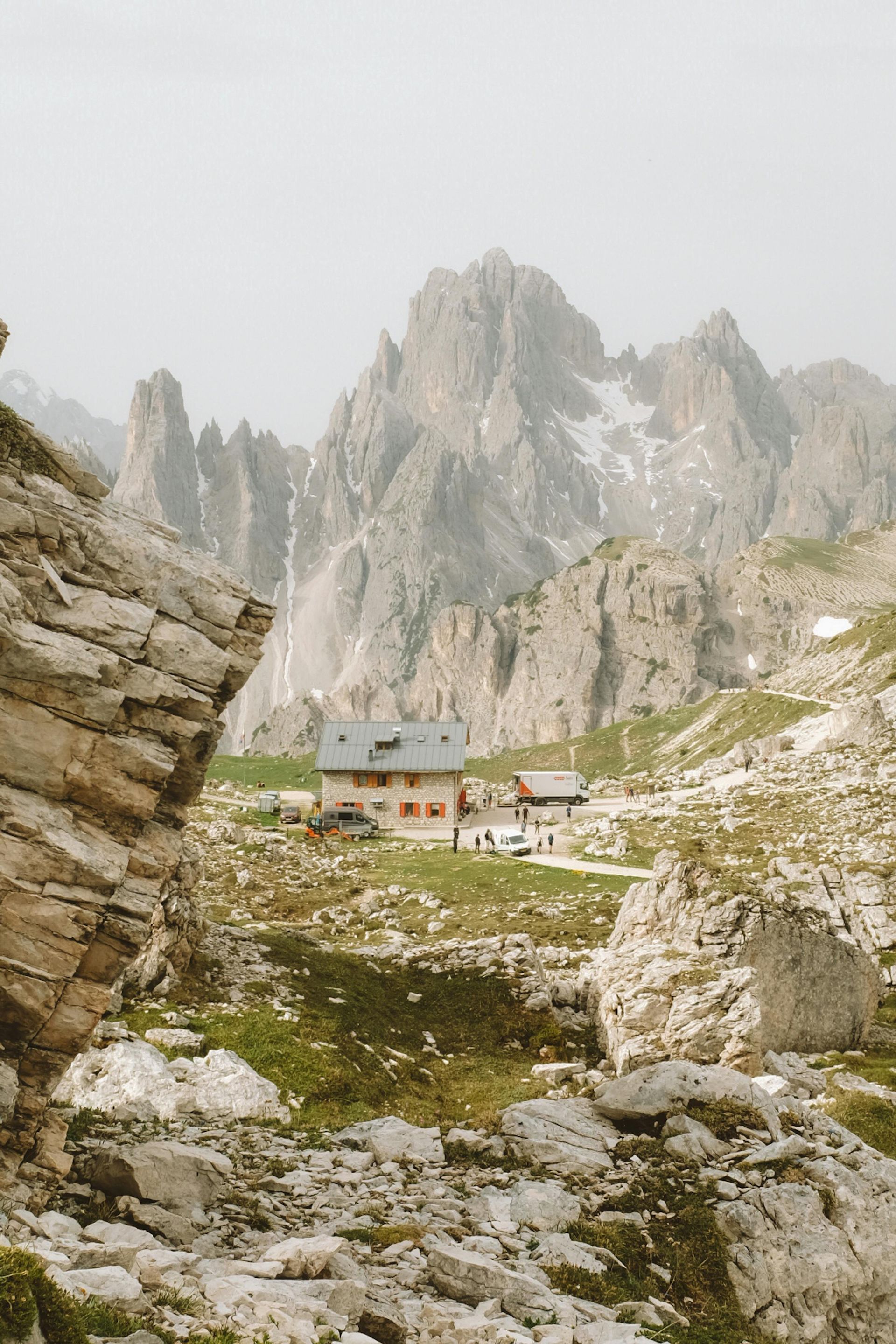 A small house in the middle of a rocky valley with The Dolomites in the background in Italy.