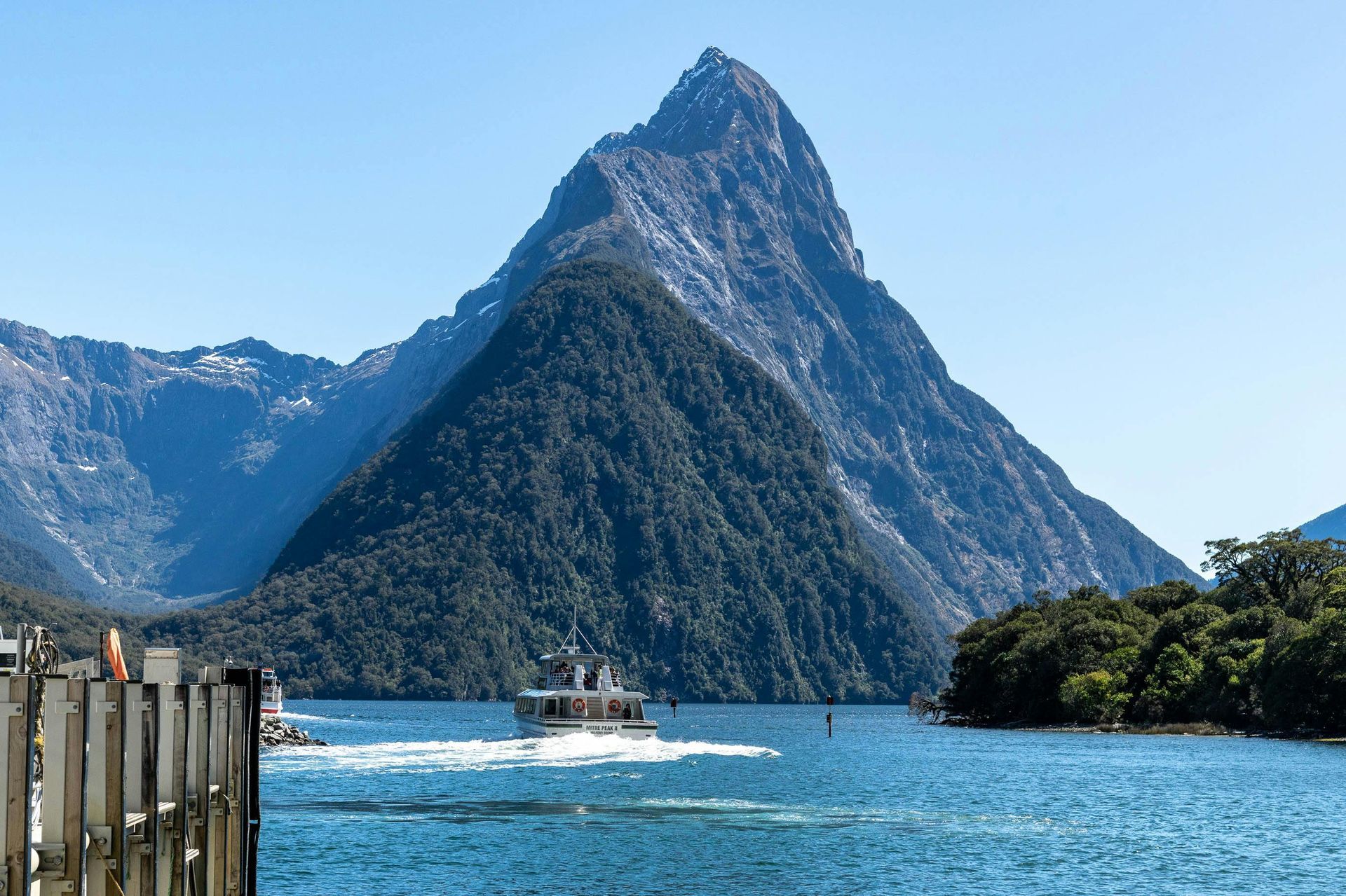 A boat is floating on a lake with a mountain in the background in New Zealand. 