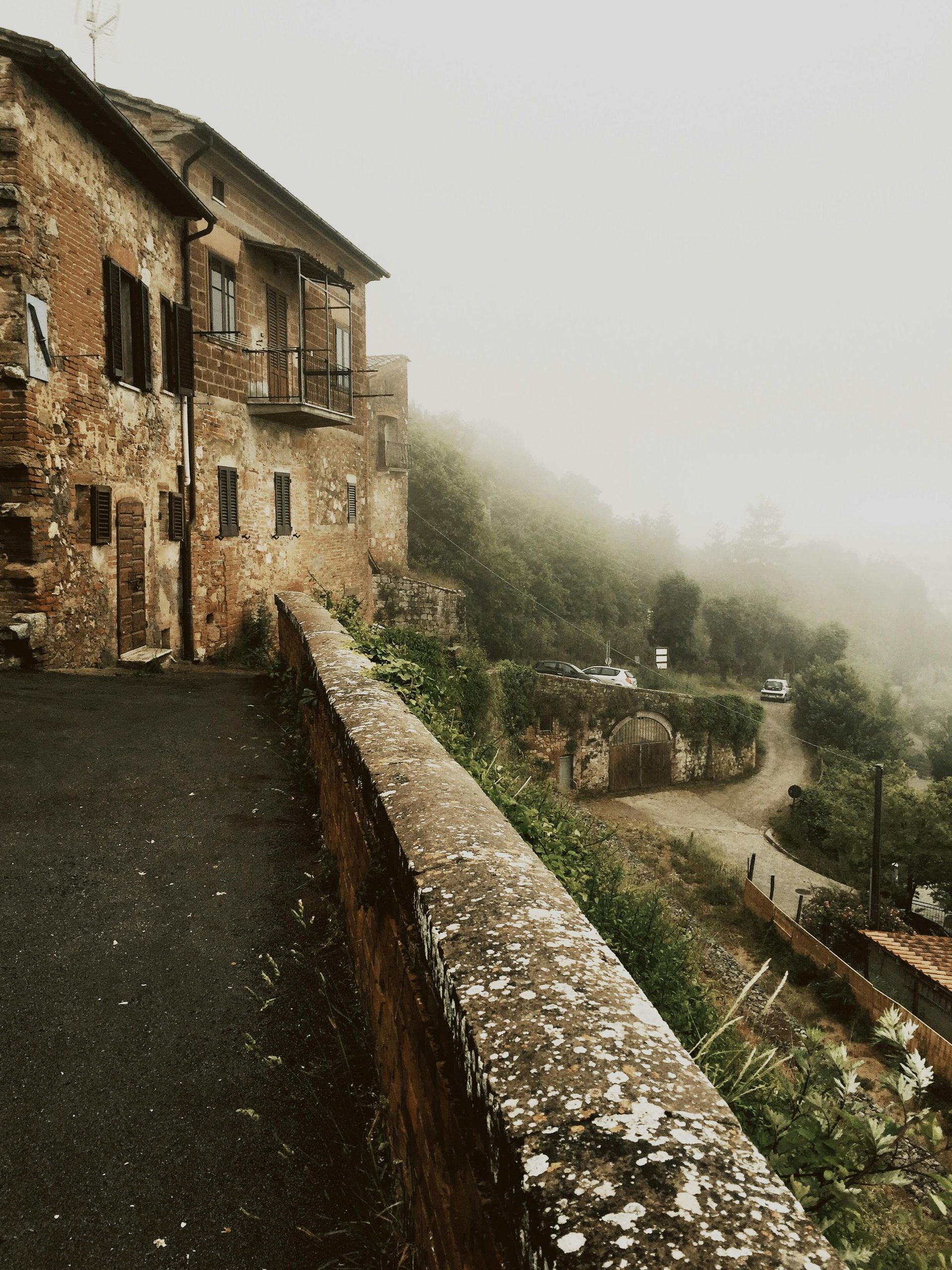 A stone building with a balcony on the side of it in Tuscany, Italy.