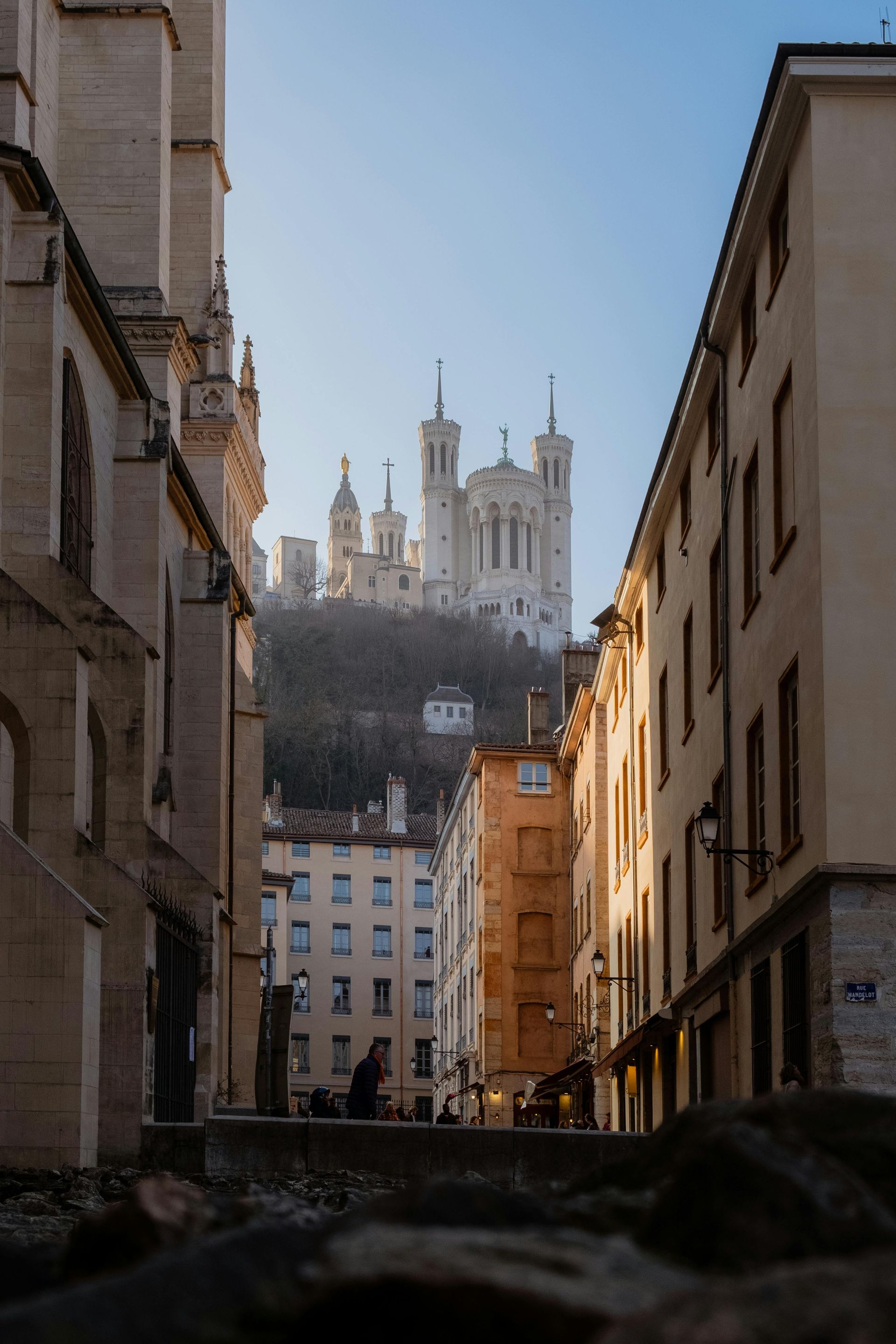 A city street with a large building in the background in Lyon, France.