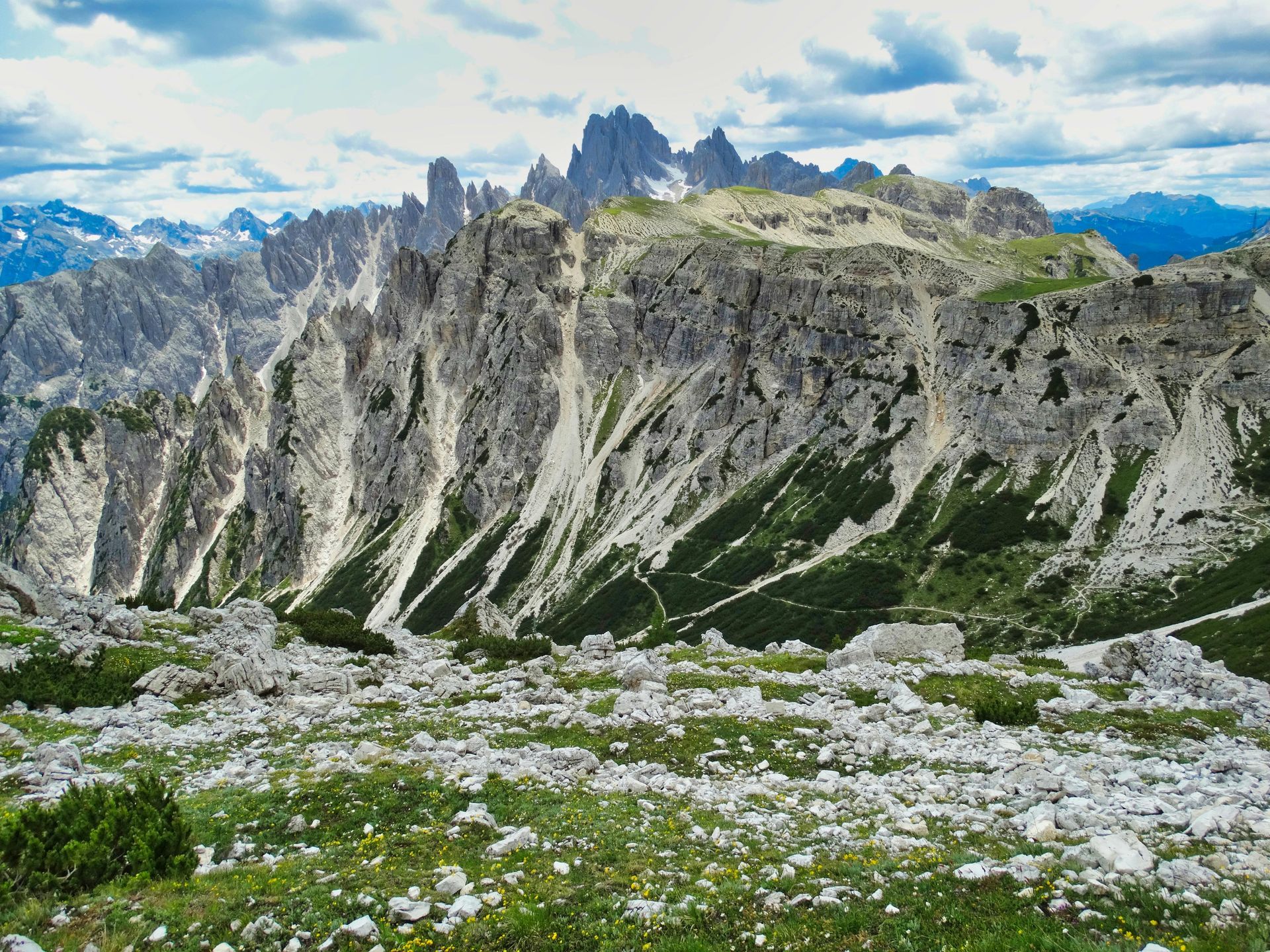 A view of The Dolomites ranges from the top of a grassy hill in Italy.