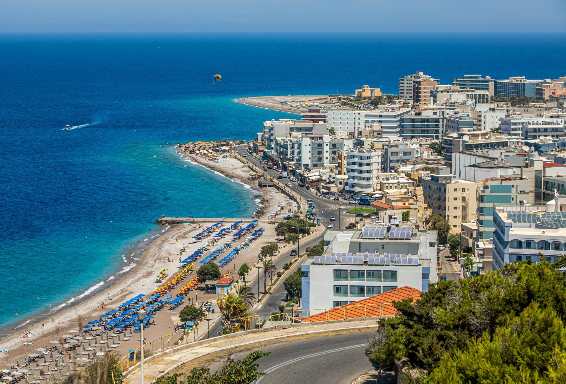 An aerial view of a city next to the Mediterranean ocean with a beach in the foreground.