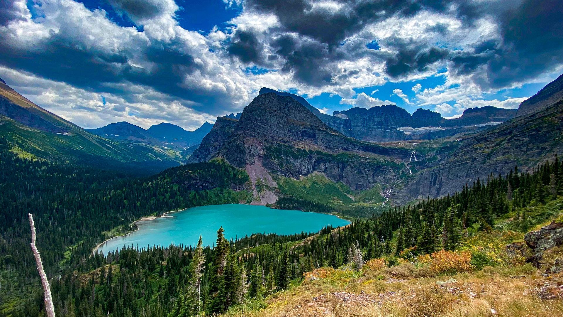 There is a lake in the middle of a mountain surrounded by trees at Glacier National Park in Montana.