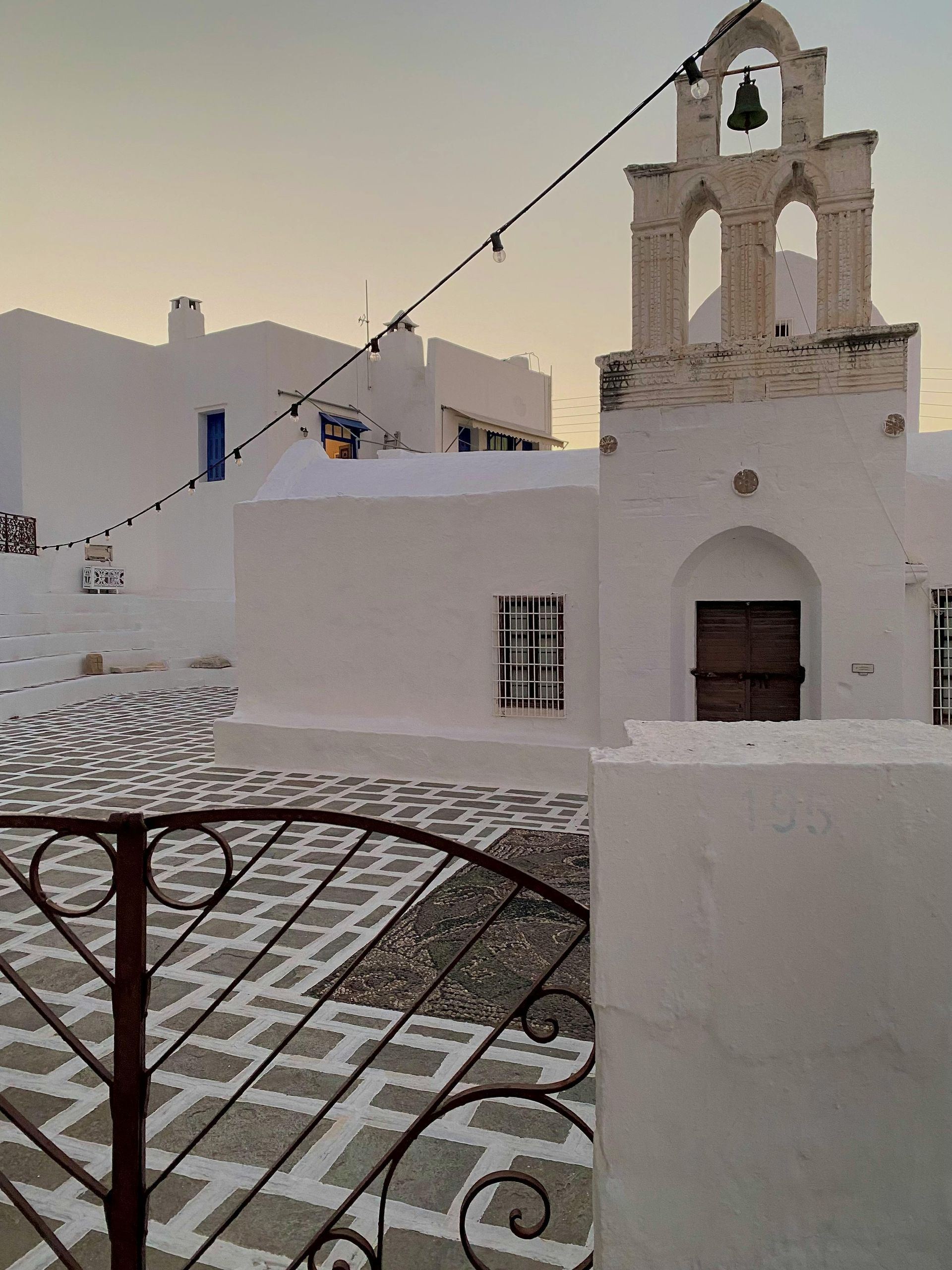 A white building with a bell on top of it in Milos, Greece.