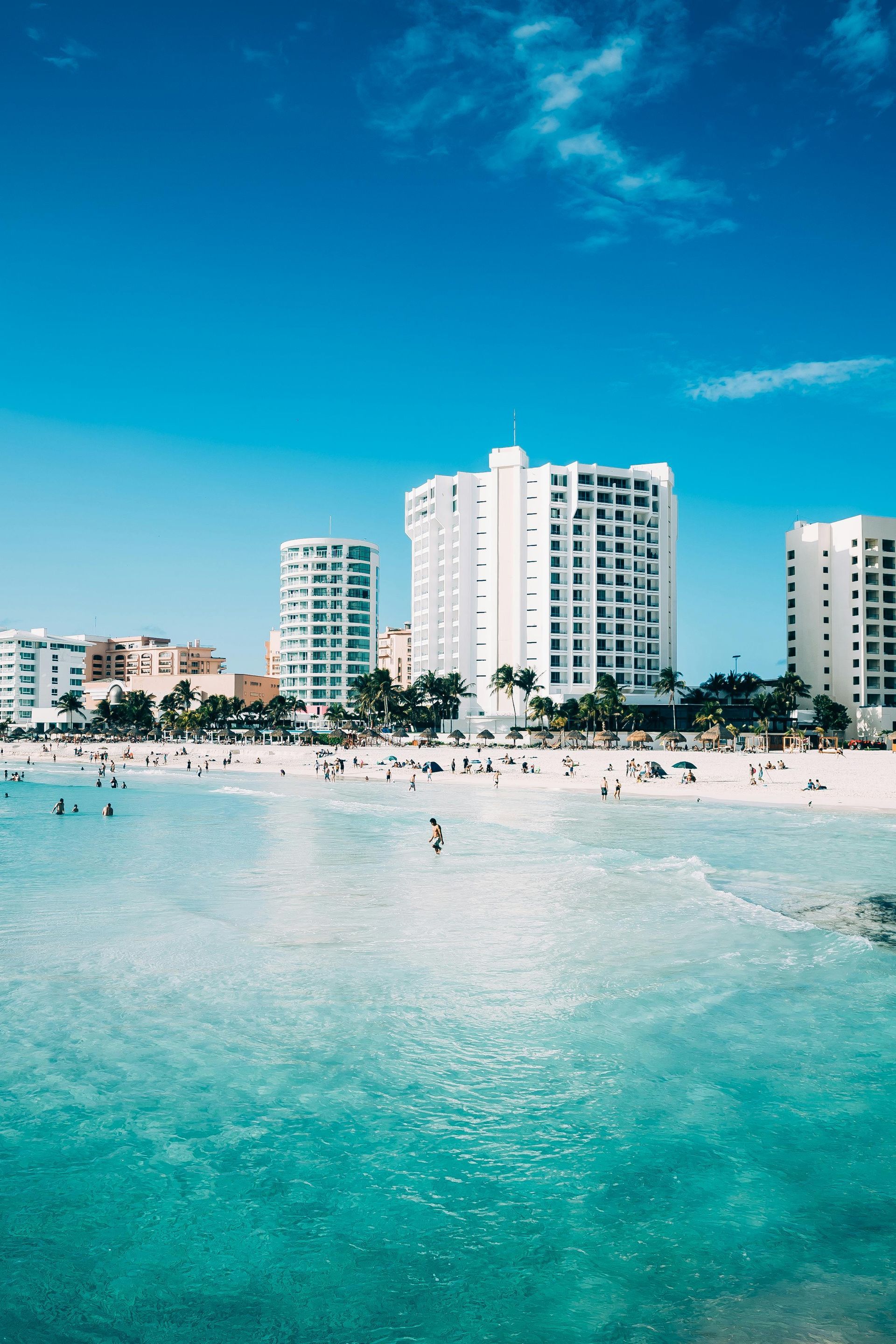 A beach with a lot of people and buildings in the background.