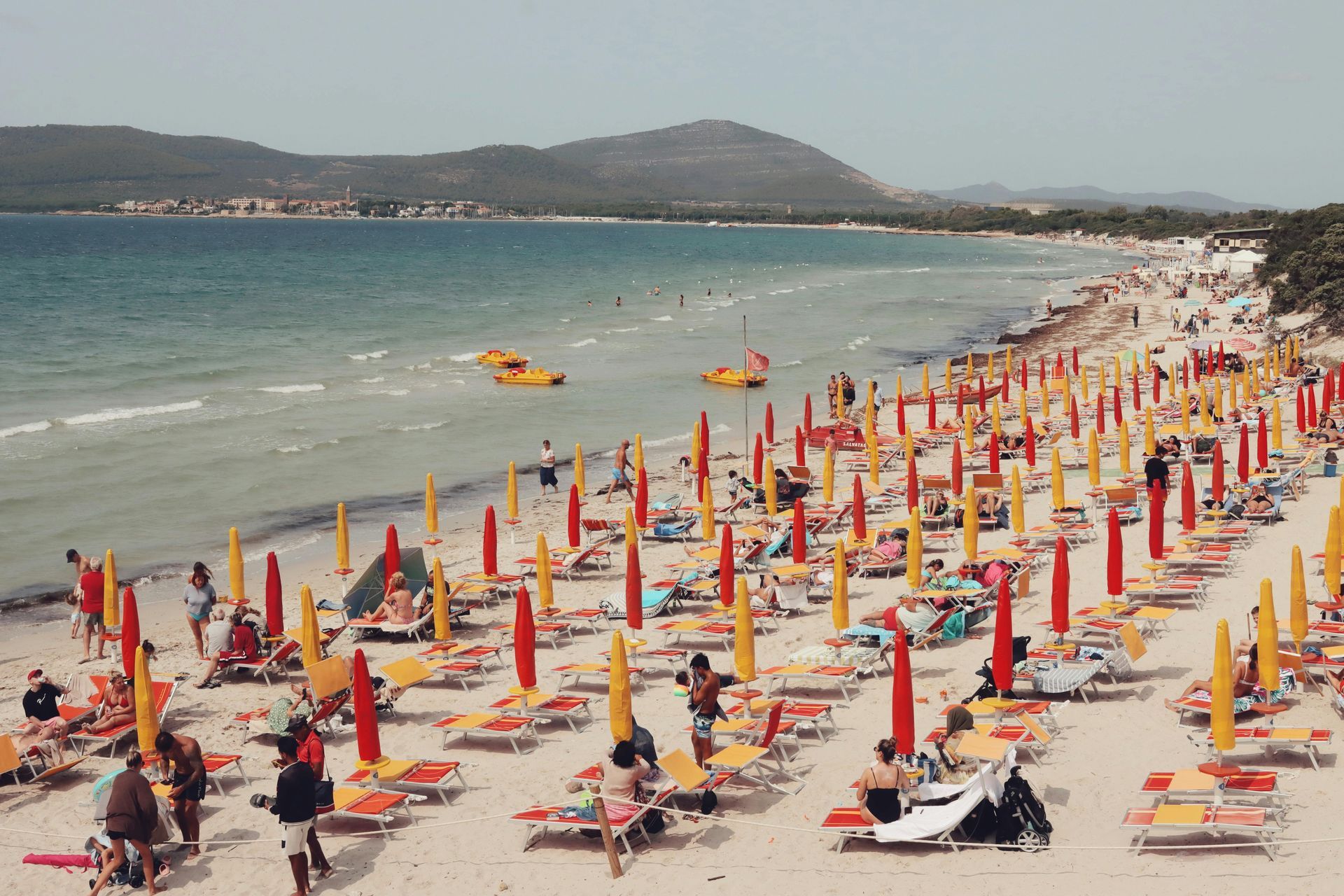 A beach filled with lots of chairs and umbrellas in Sardinia, Italy.