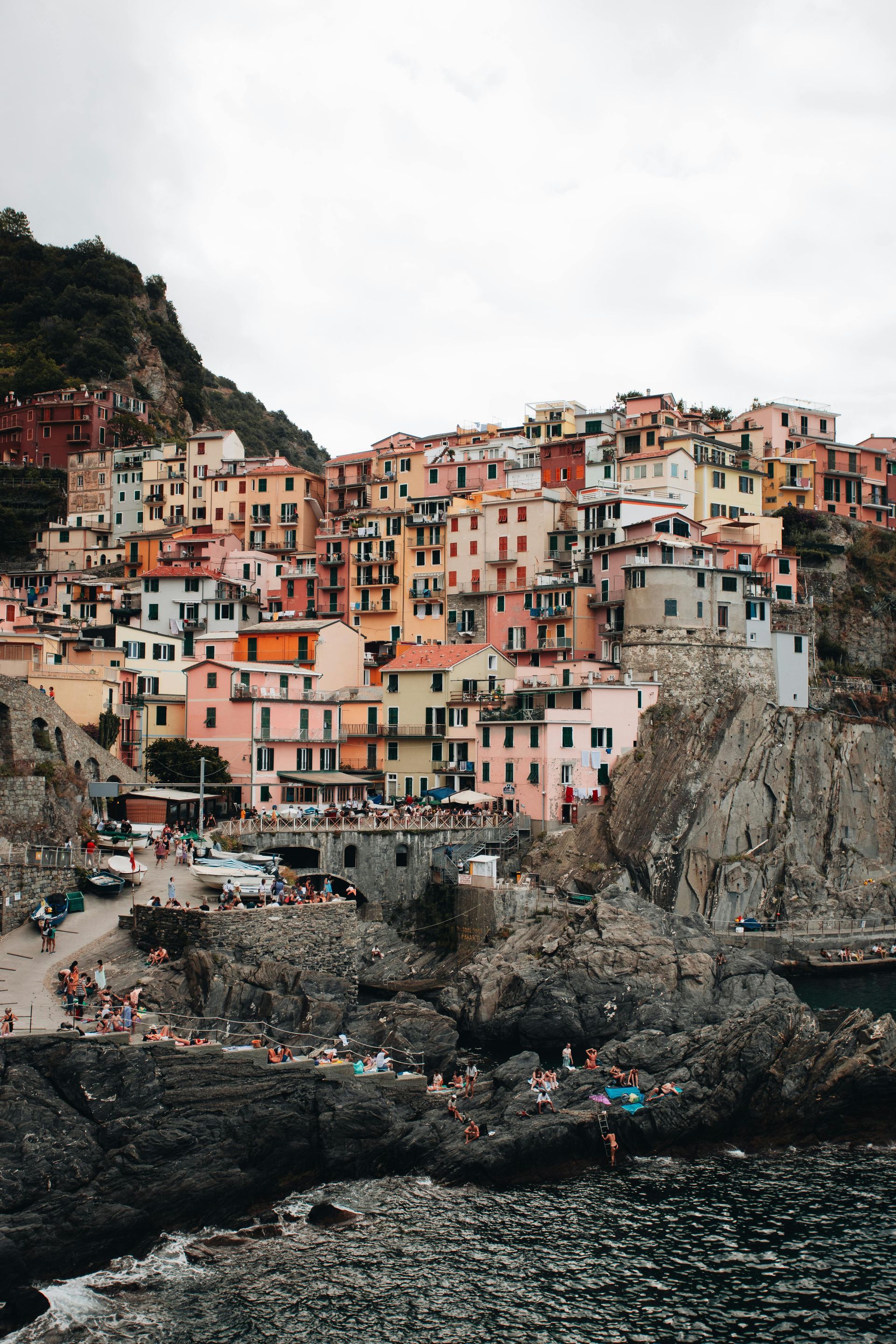 Cinque Terre sitting on top of a rocky hill next to a body of water in Italy.