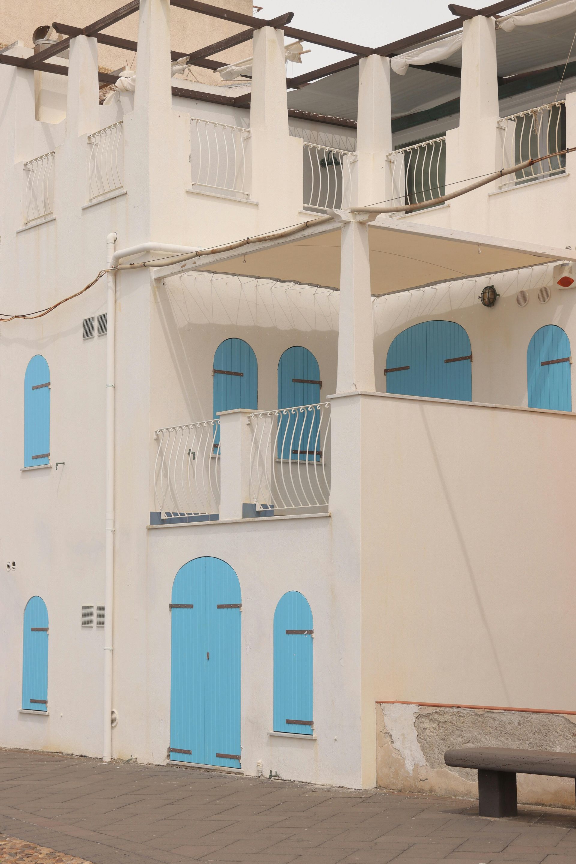 A white building with blue shutters on the windows in Sardinia, Italy.