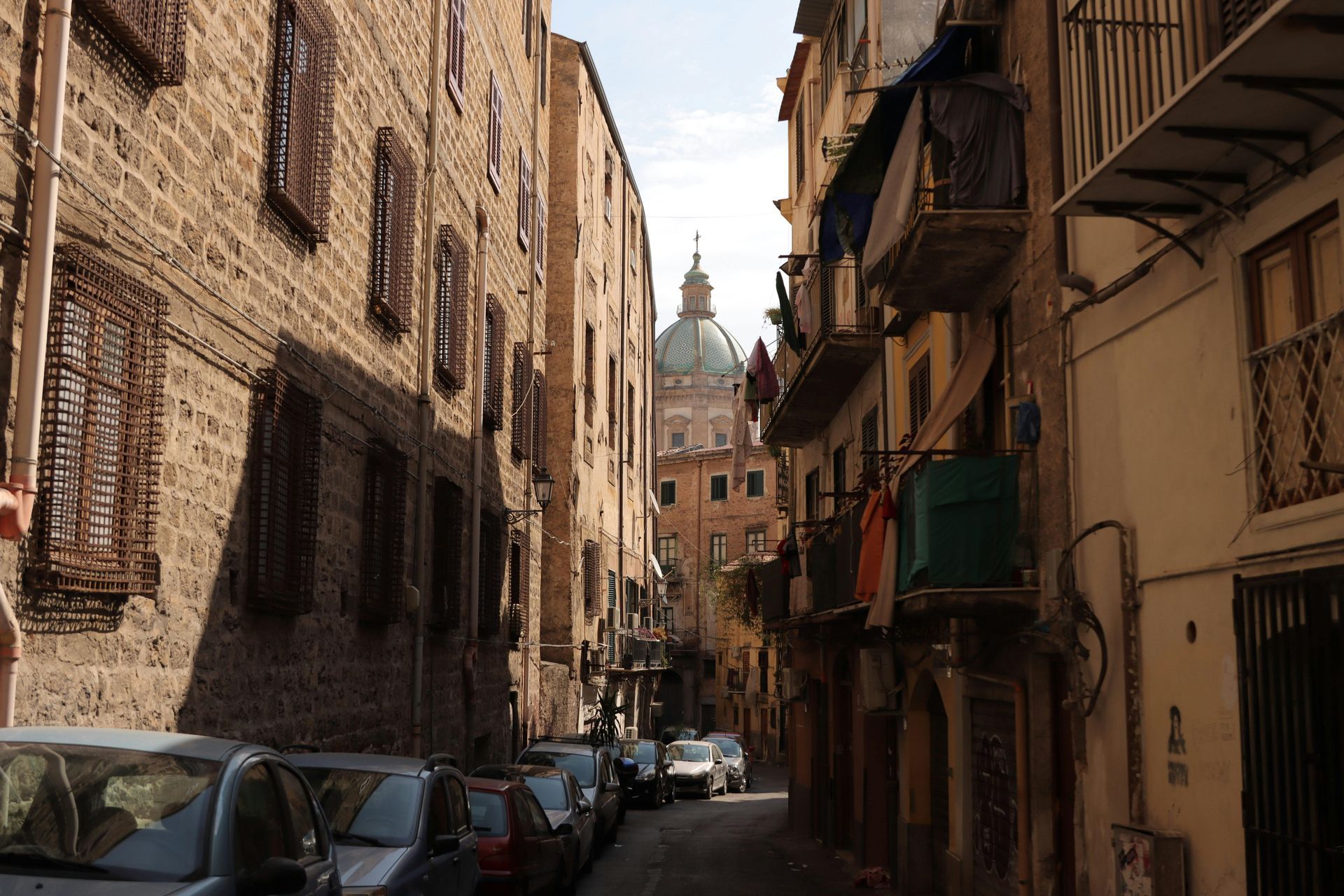 A narrow street with a dome in the background in Sicily, Italy.