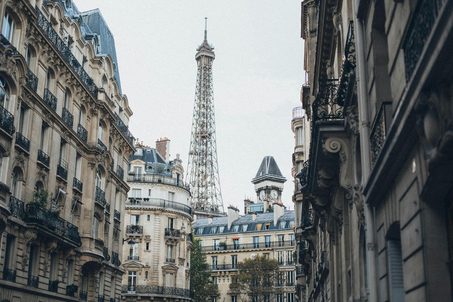 The eiffel tower is visible between two buildings in paris.