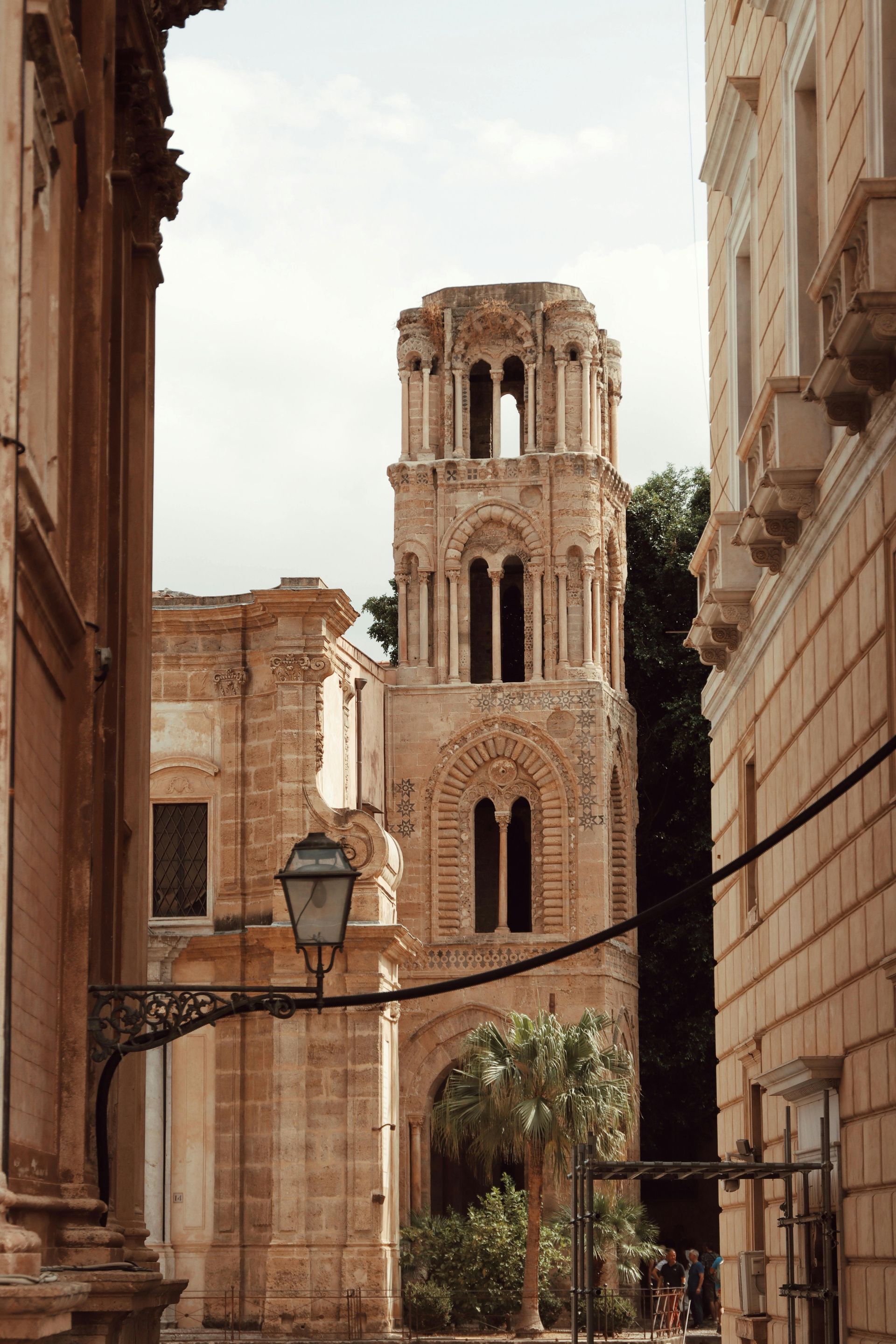 A narrow alleyway with a tower in the middle of it in Sicily, Itlay.