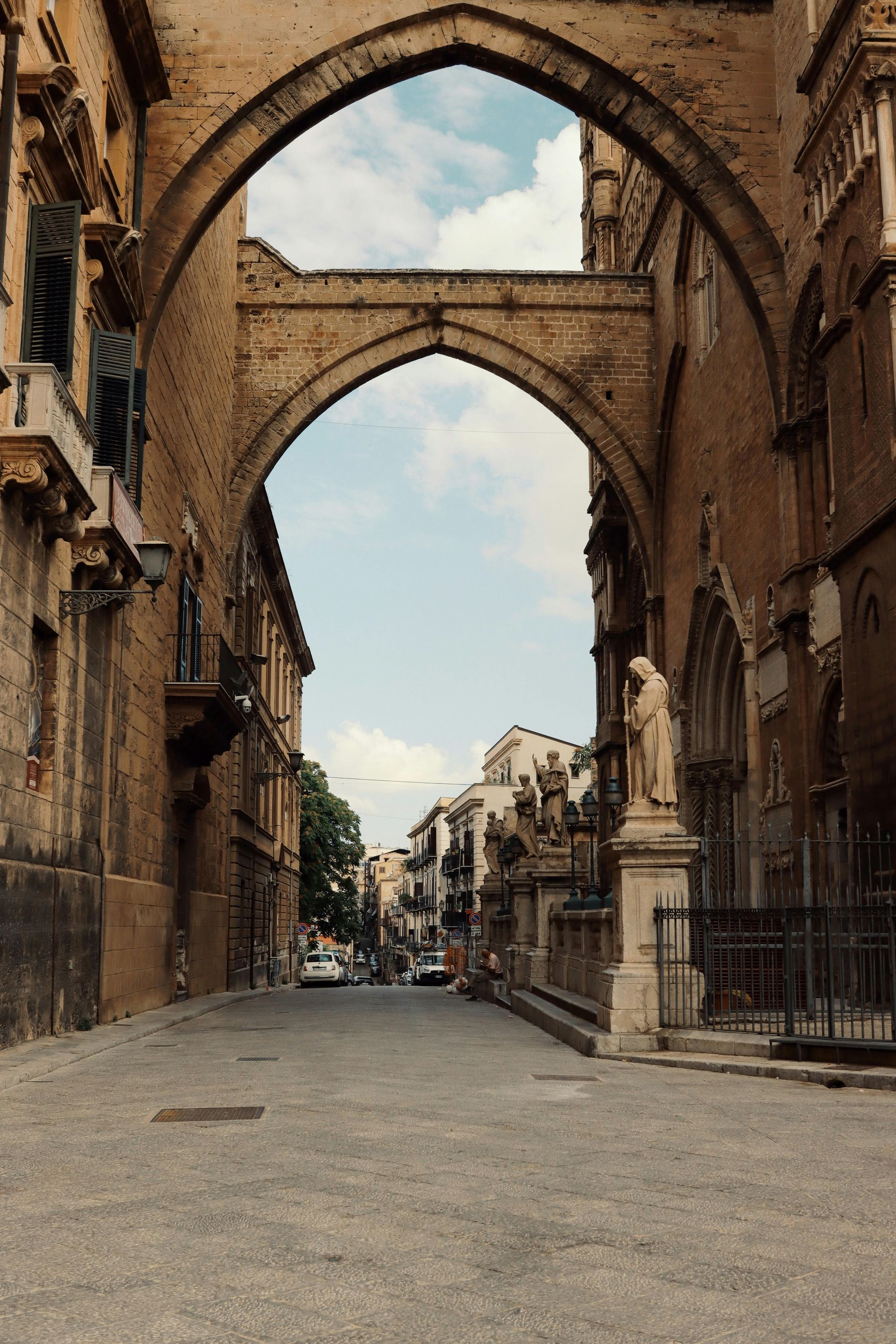 A view of a city street through an archway between two buildings in Sicily, Italy.