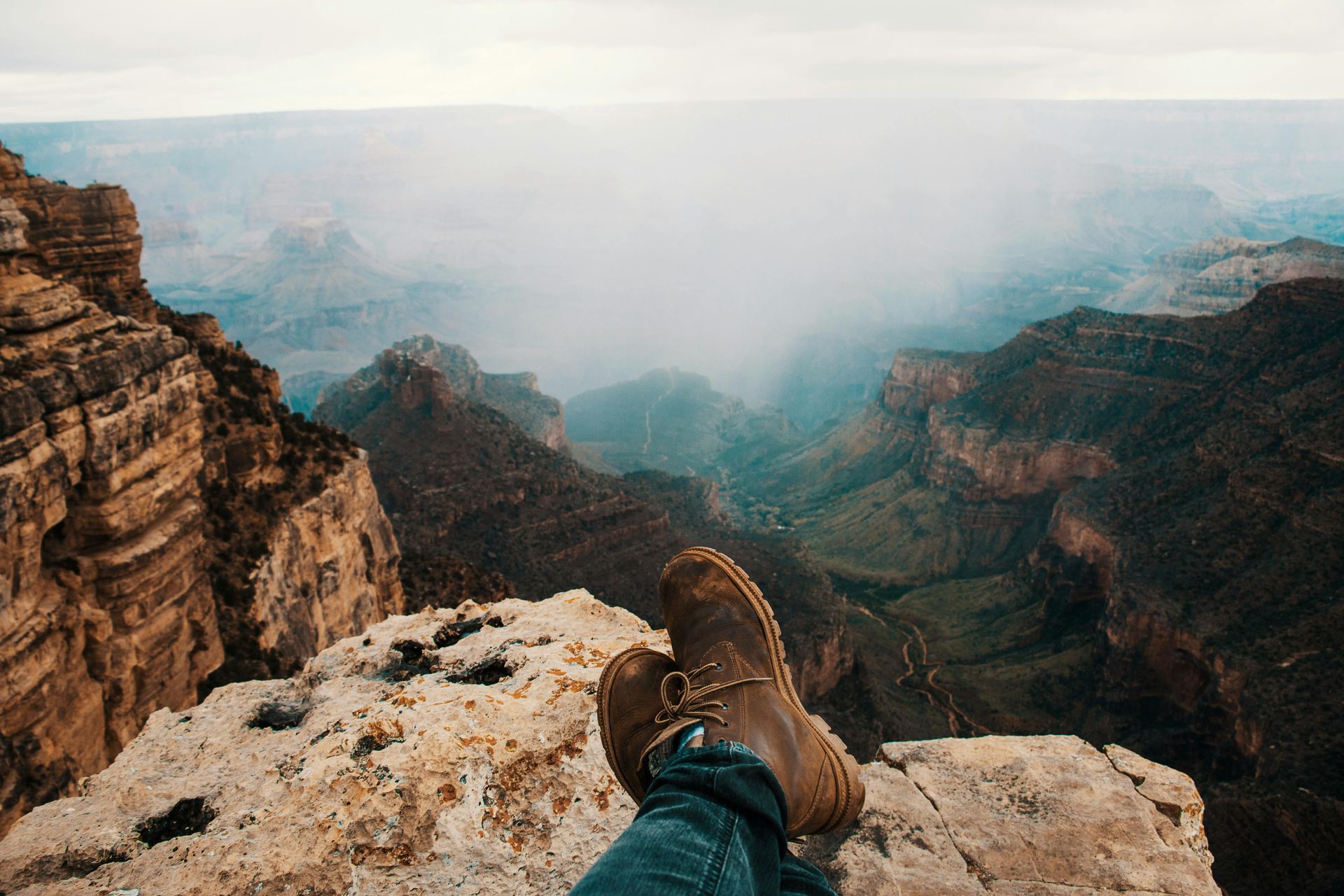 A person 's feet are resting on the edge of a cliff overlooking the Grand Canyon in Arizona.