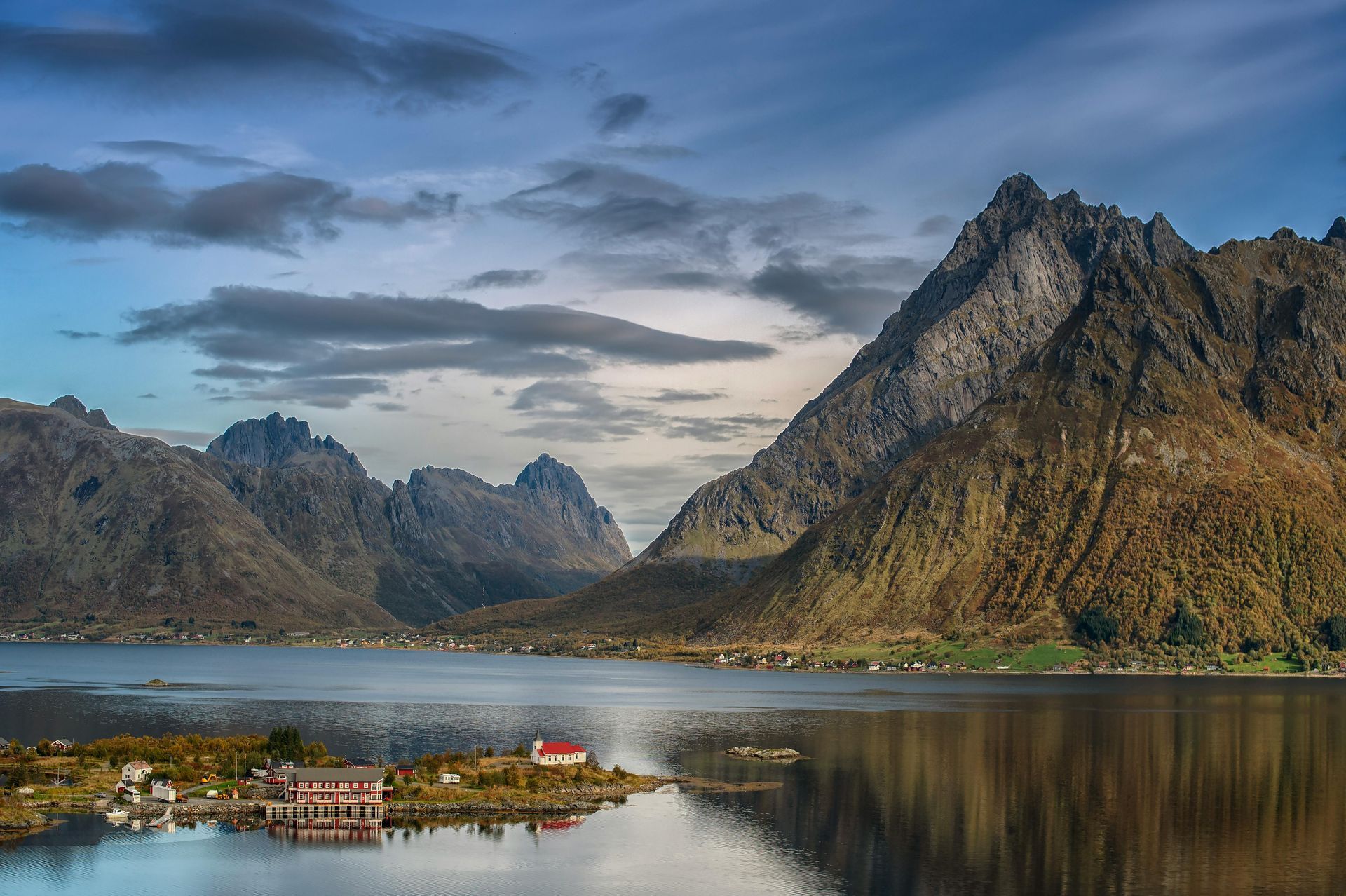 A lake with mountains in the background and a house in the foreground  on the Norwegian Coast.