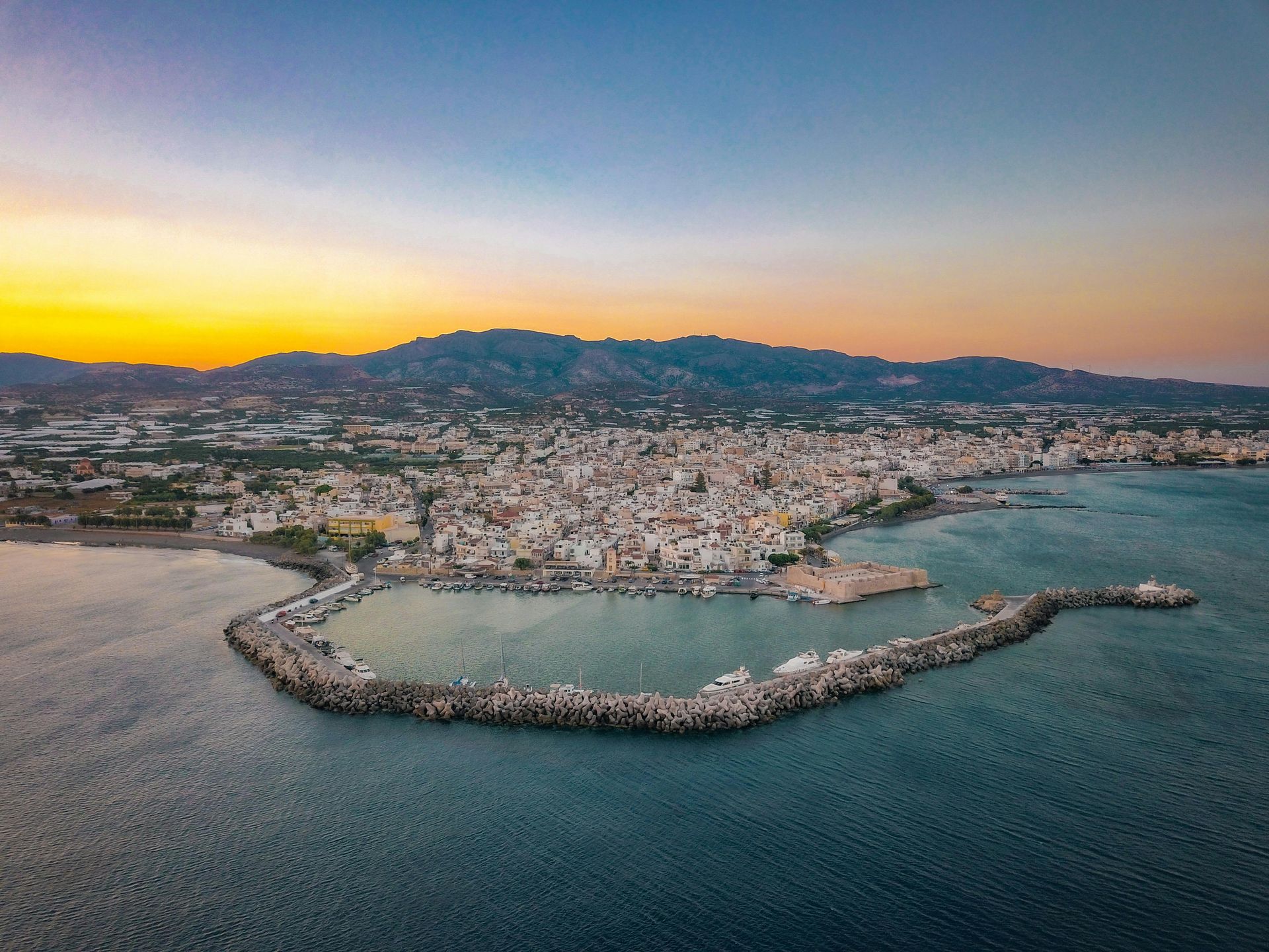 An aerial view of a city in the middle of the ocean at sunset in Crete, Greece.