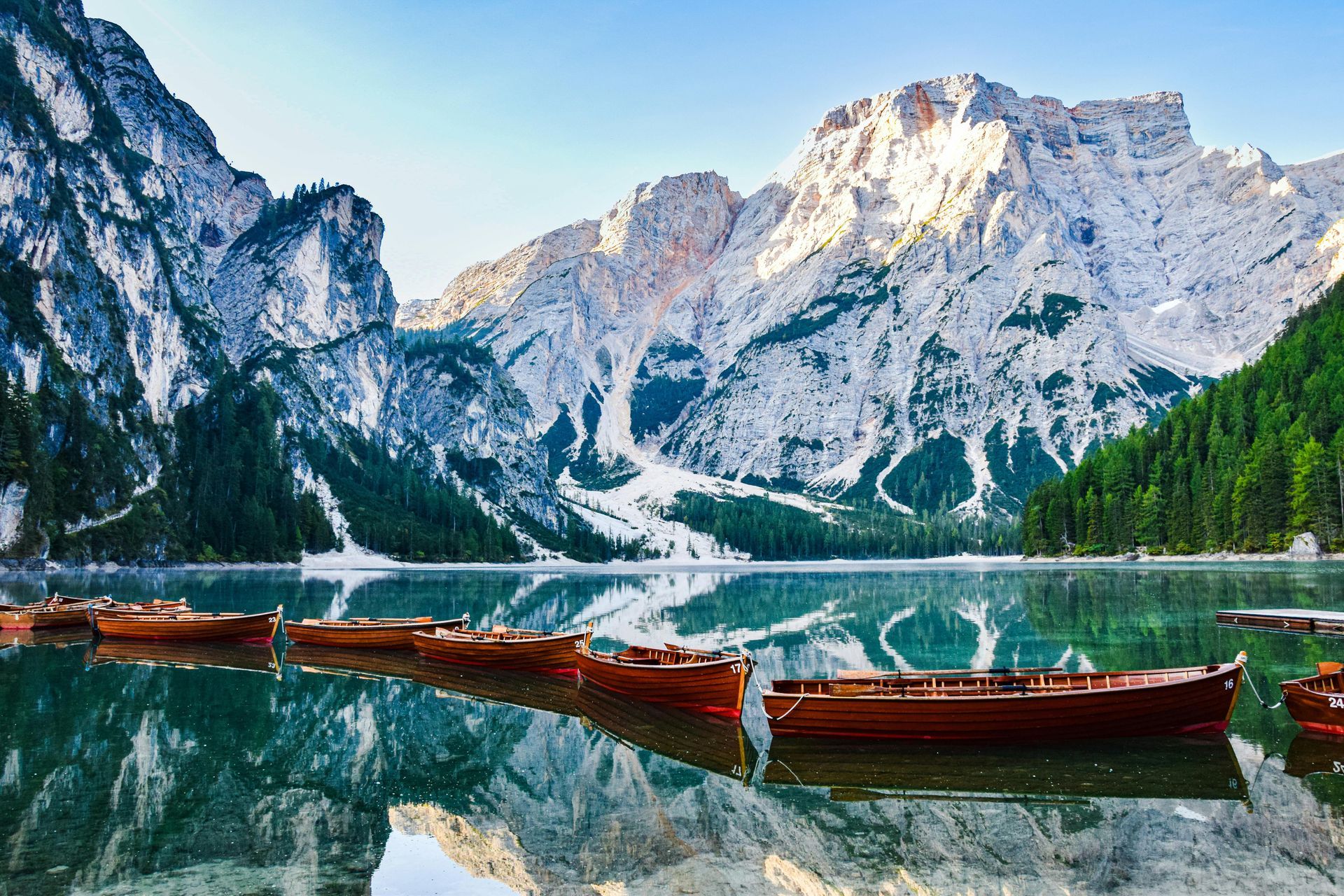 A group of boats are floating on a lake in The Dolomites in Italy.