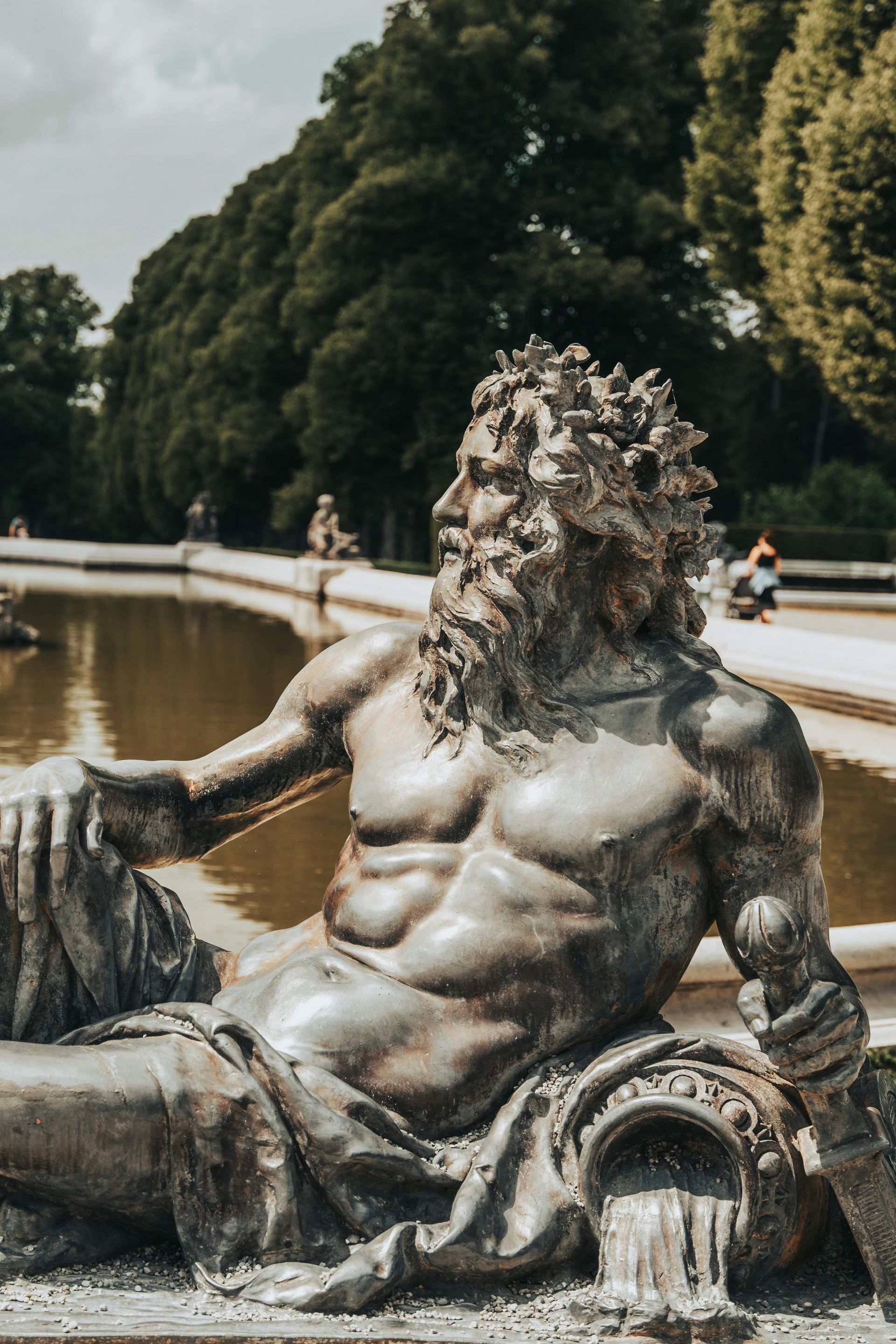 A statue of a man with a beard is sitting next to a pond in northern France.