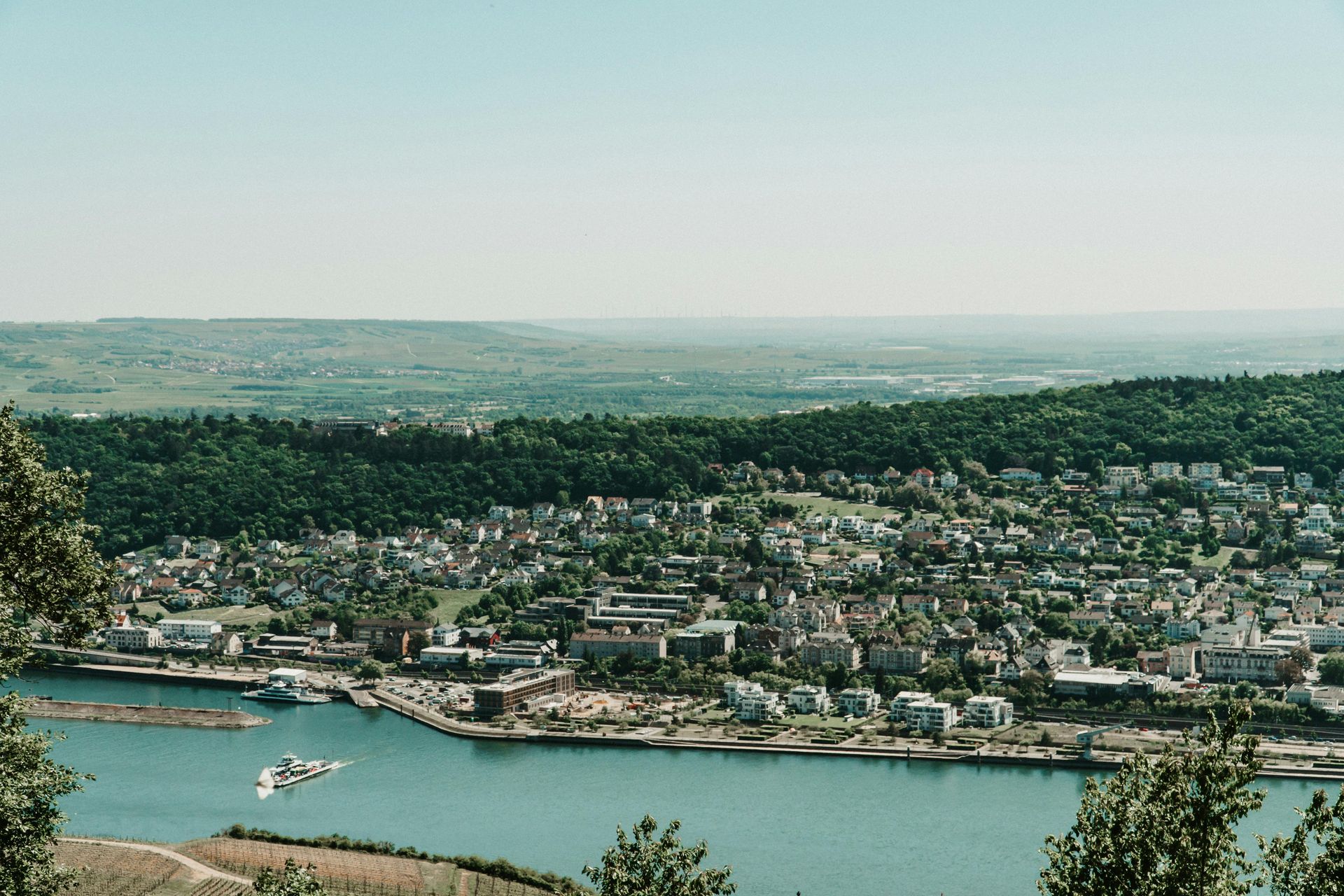 An aerial view of a city and The Rhine River with a boat in the water.