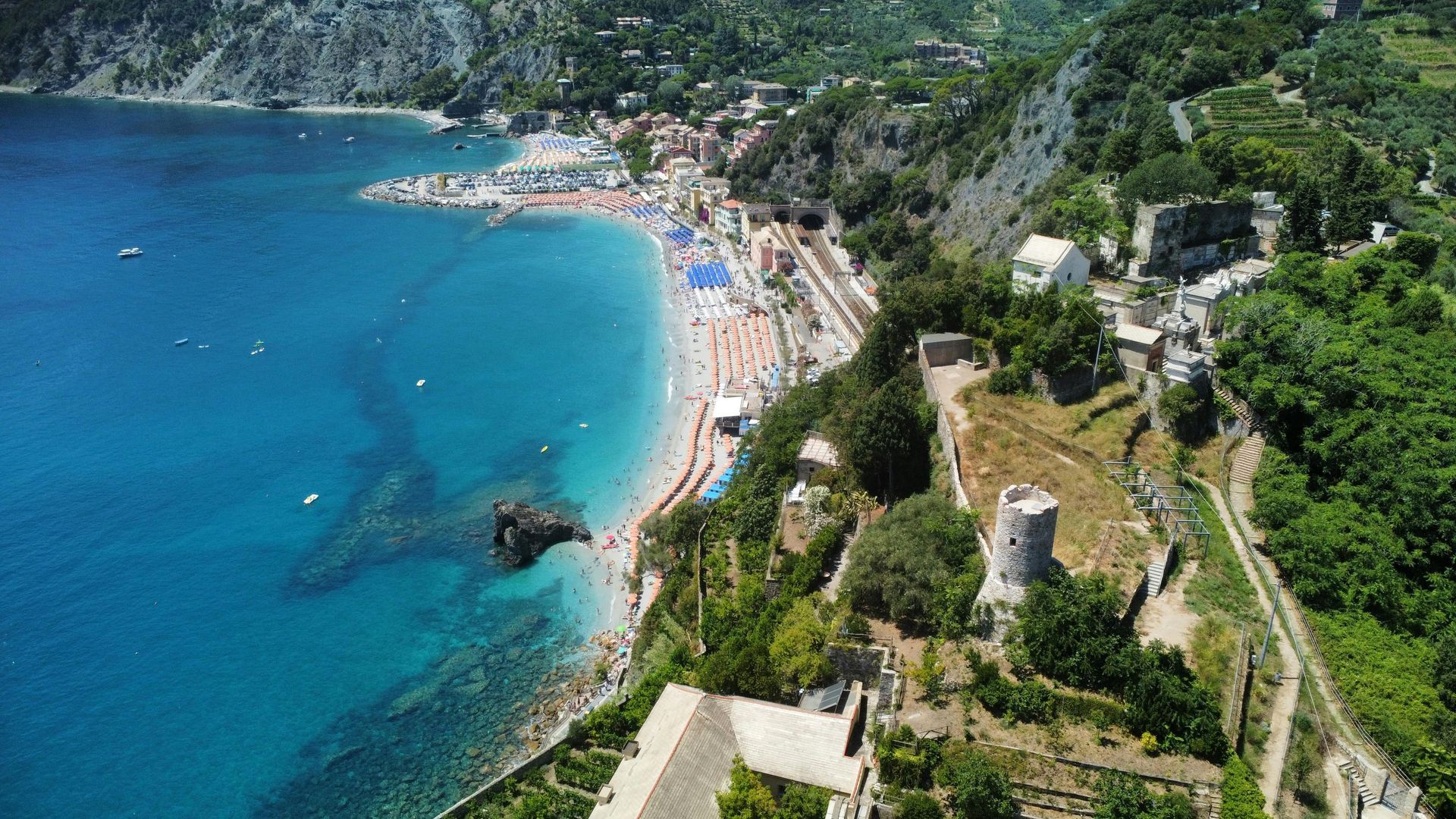 An aerial view of a beach surrounded by trees and a body of water in Cinque Terre, Italy.