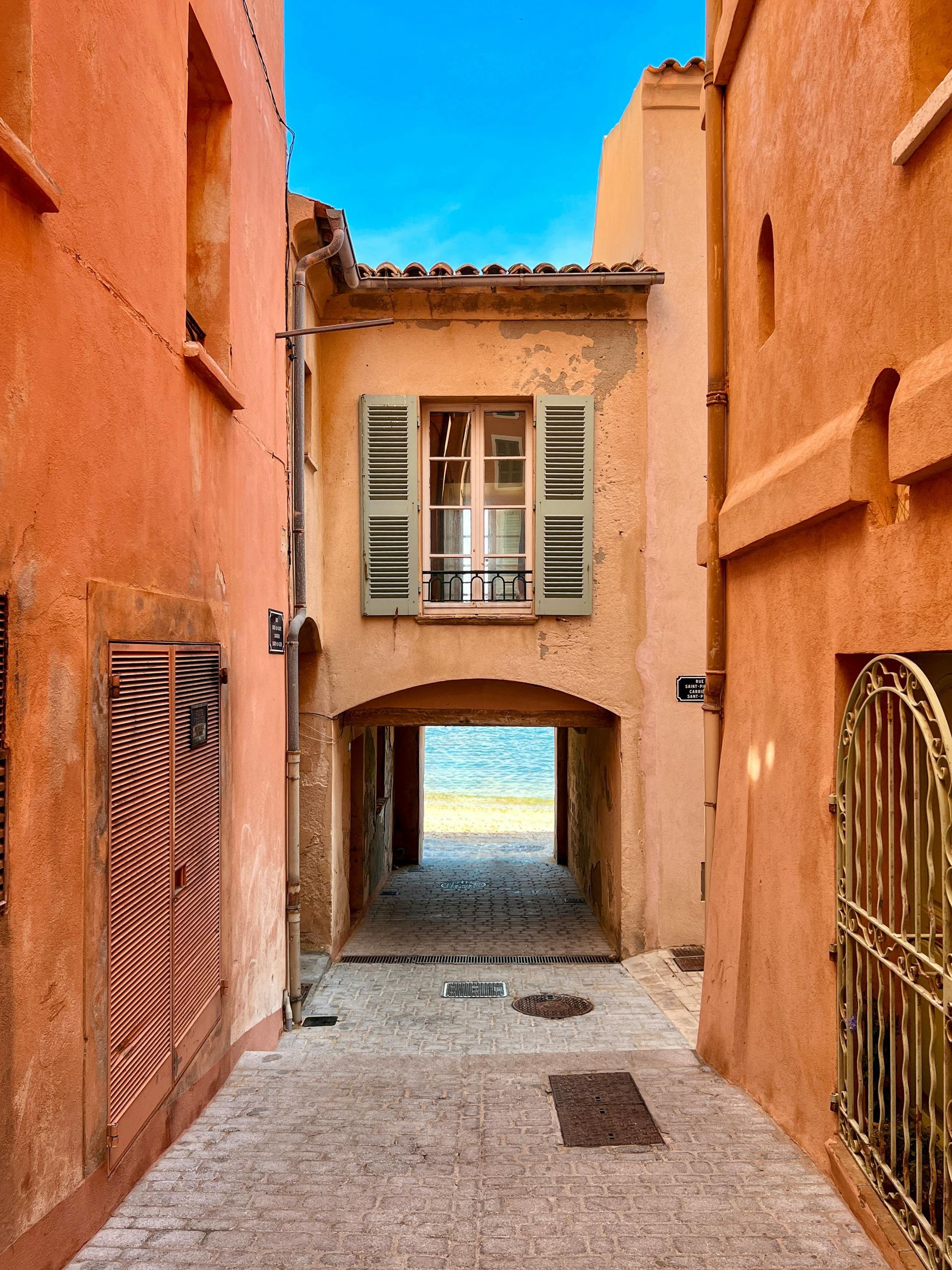 A narrow alleyway between two buildings leading to the beach in Côte d’Azur.