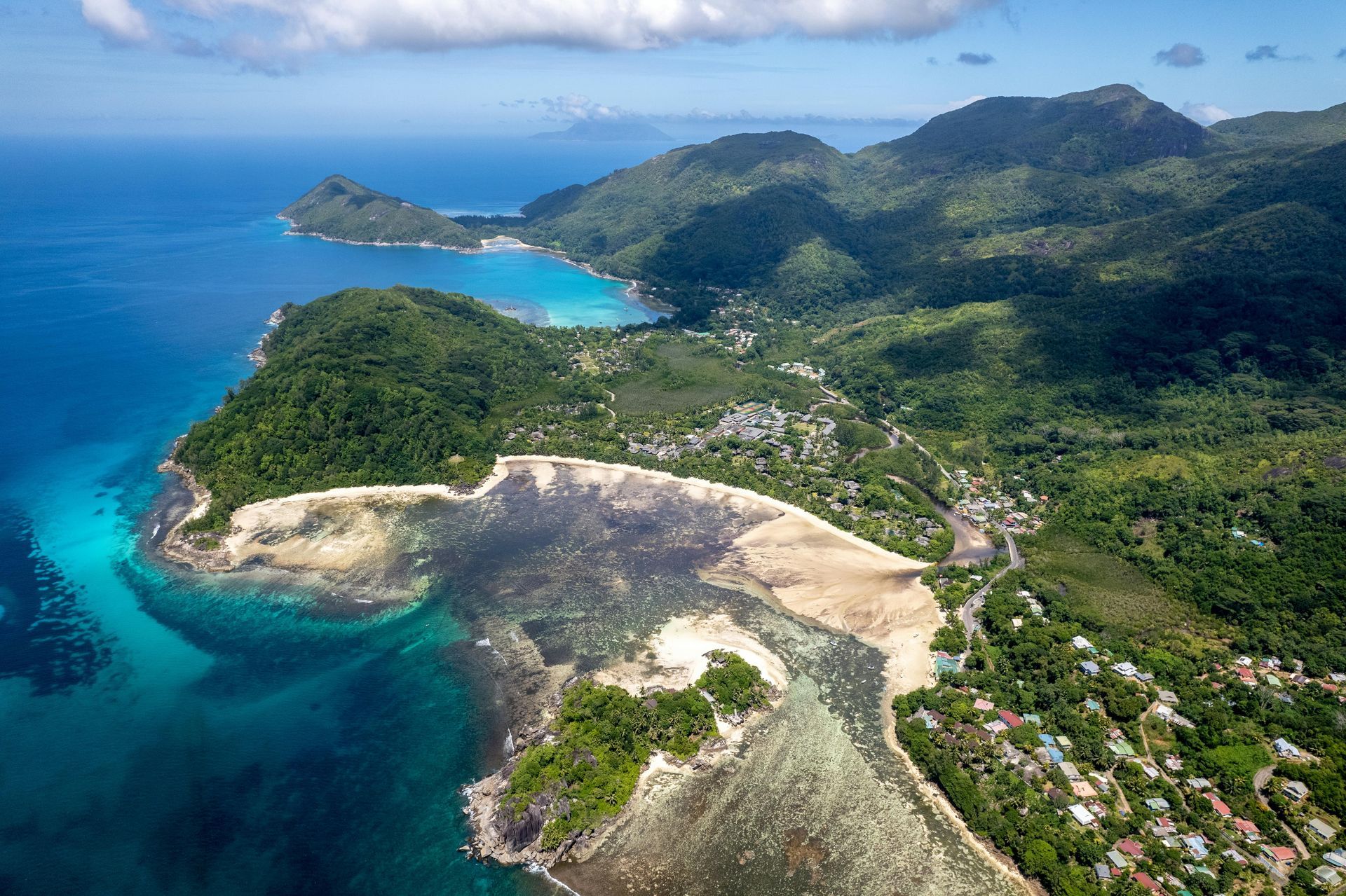 An aerial view of Seychelles Island in the middle of the ocean surrounded by mountains.