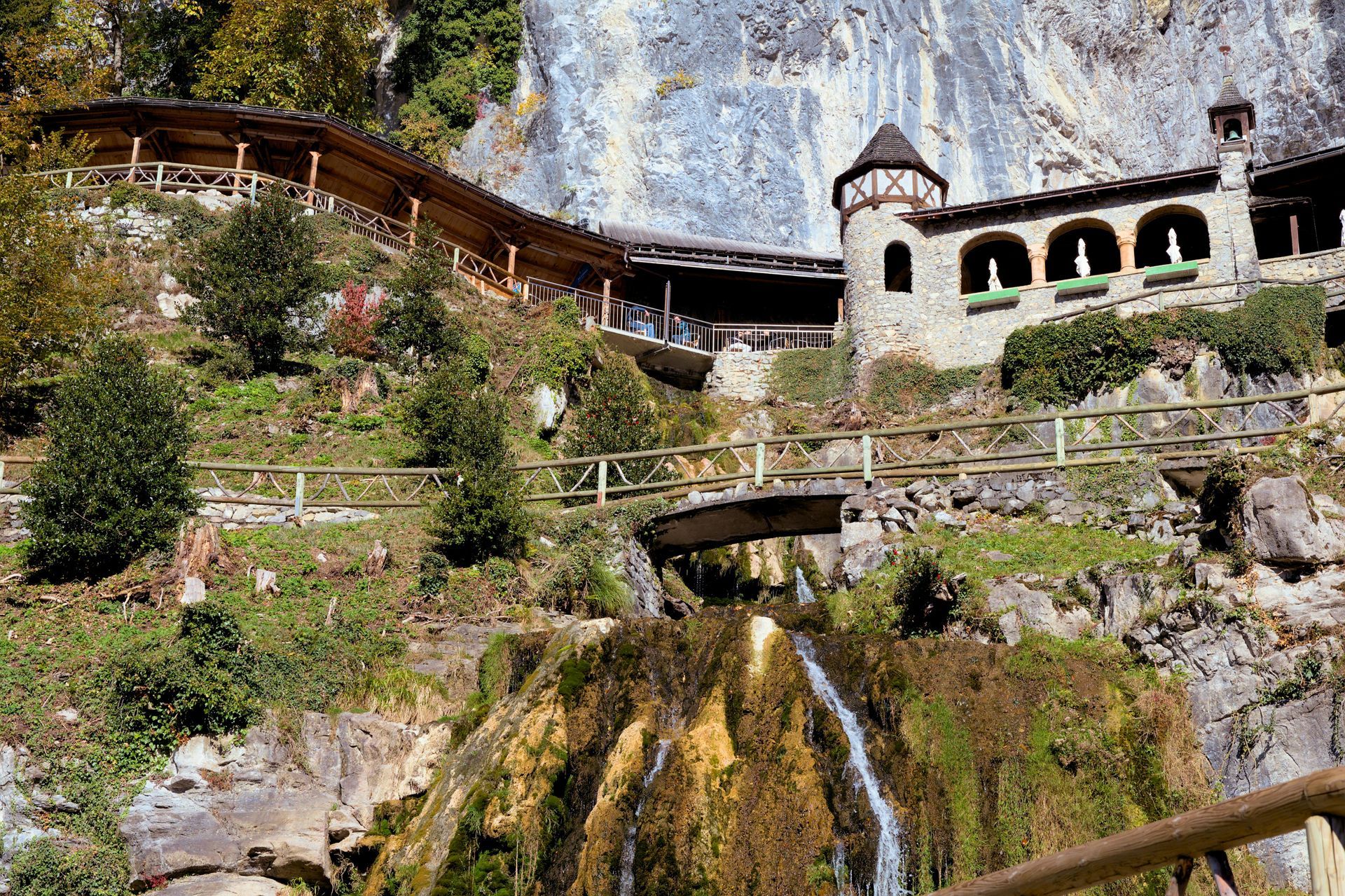 There is a waterfall in the foreground and a building in the background in Switzerland.