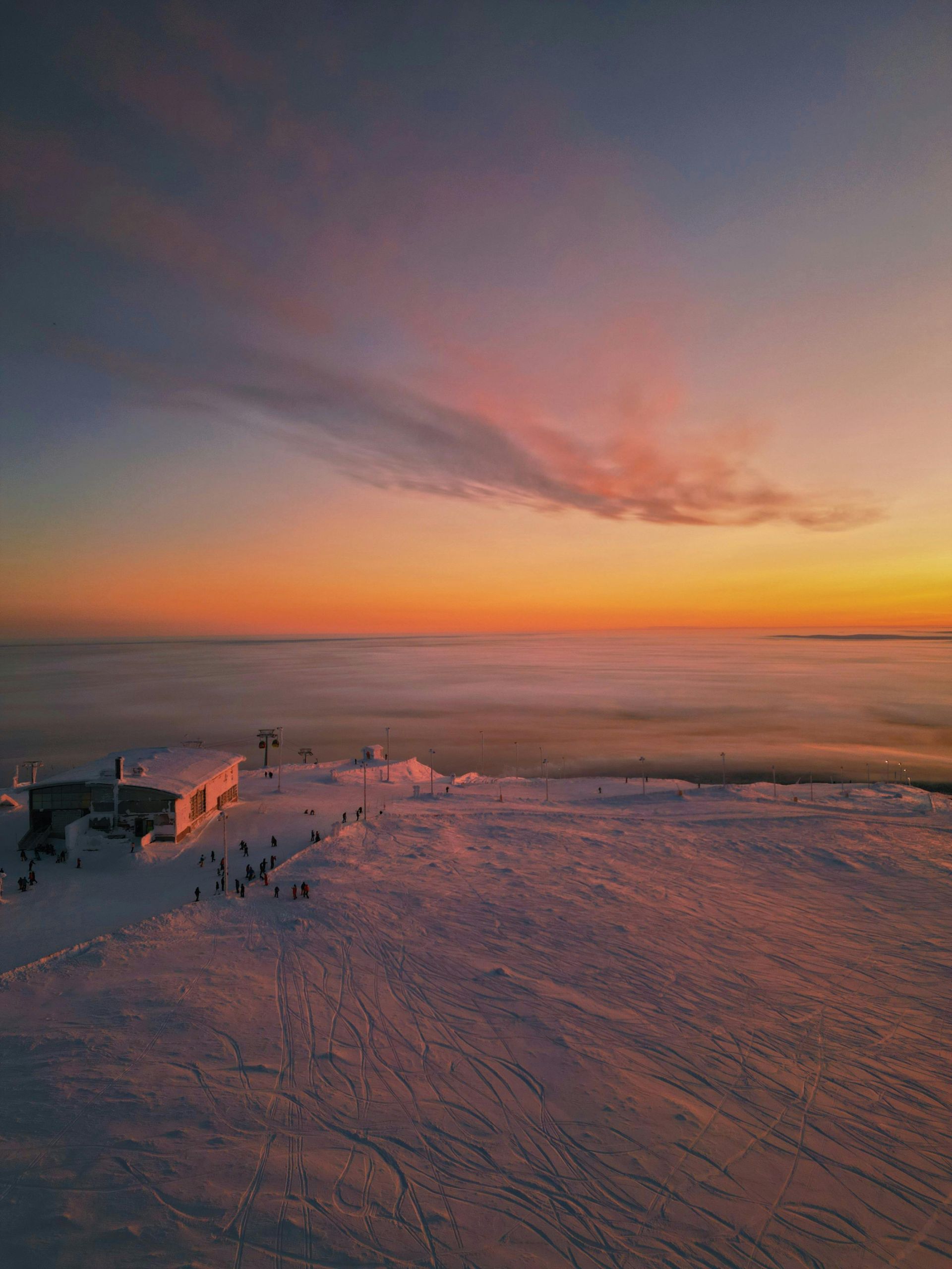 An aerial view of a snowy mountain at sunset in Finland.