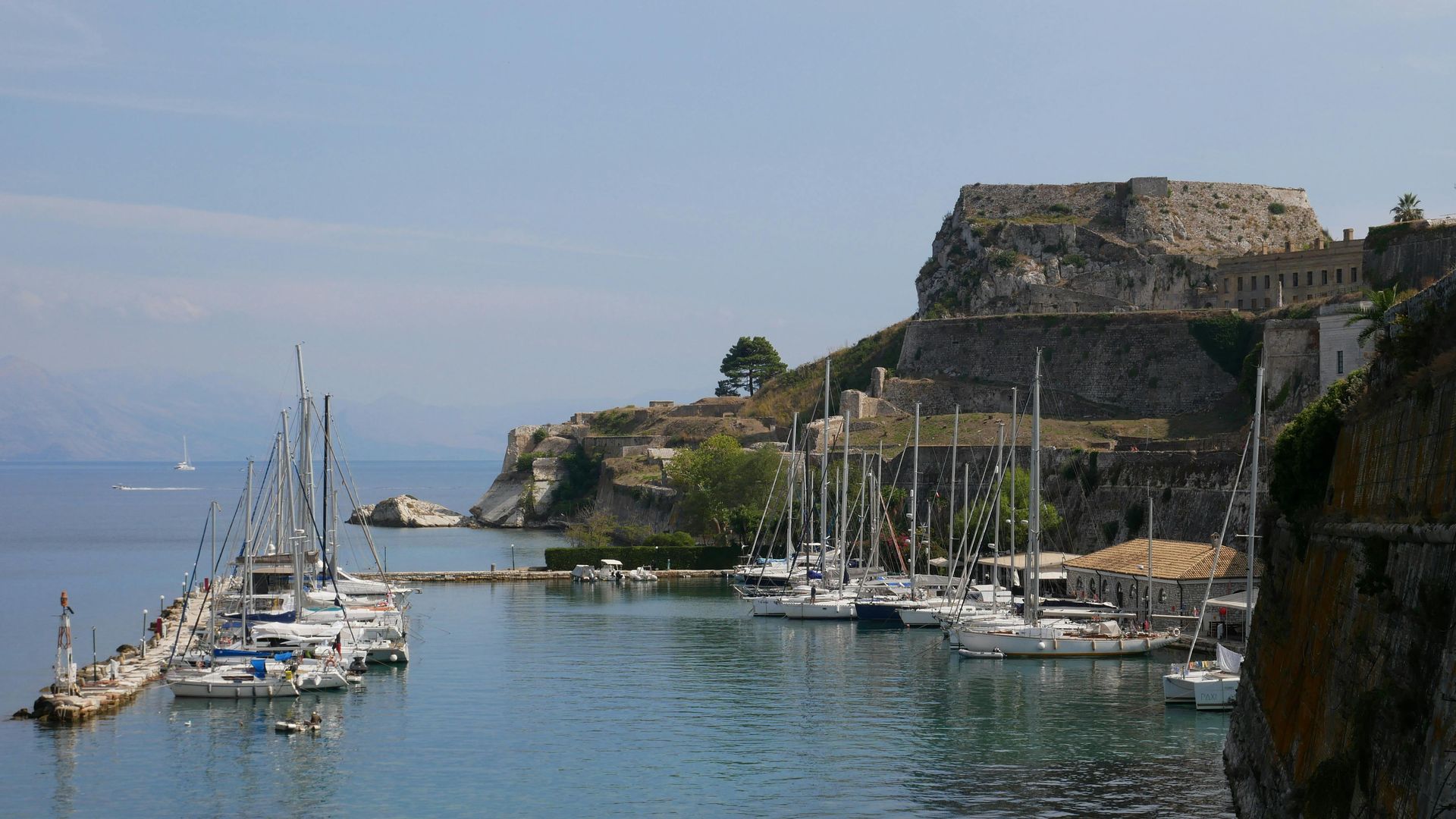 A harbor with boats and a castle in the background in Corfu, Greece.