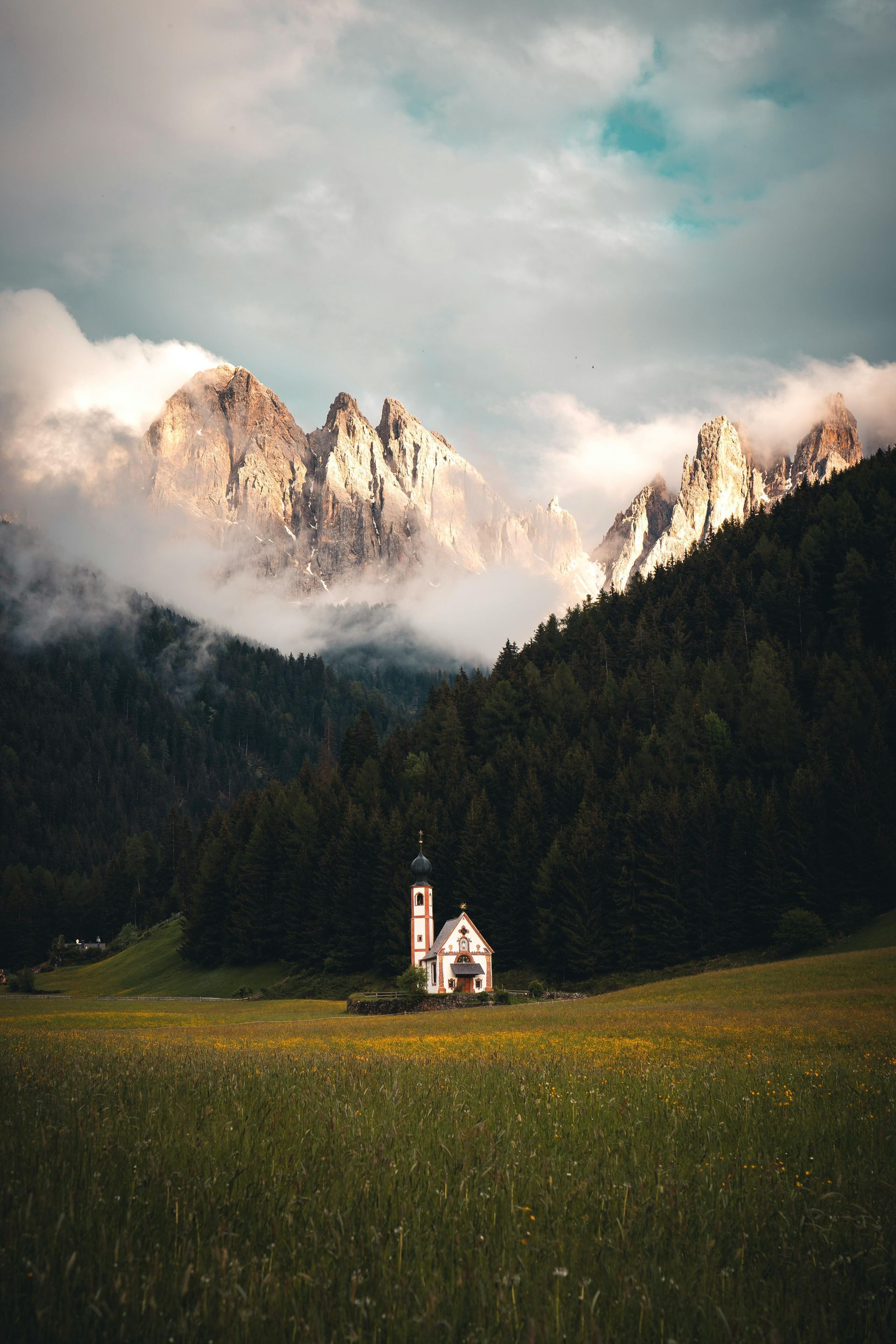 A small church in the middle of a field The Dolomites in the background in Italy.