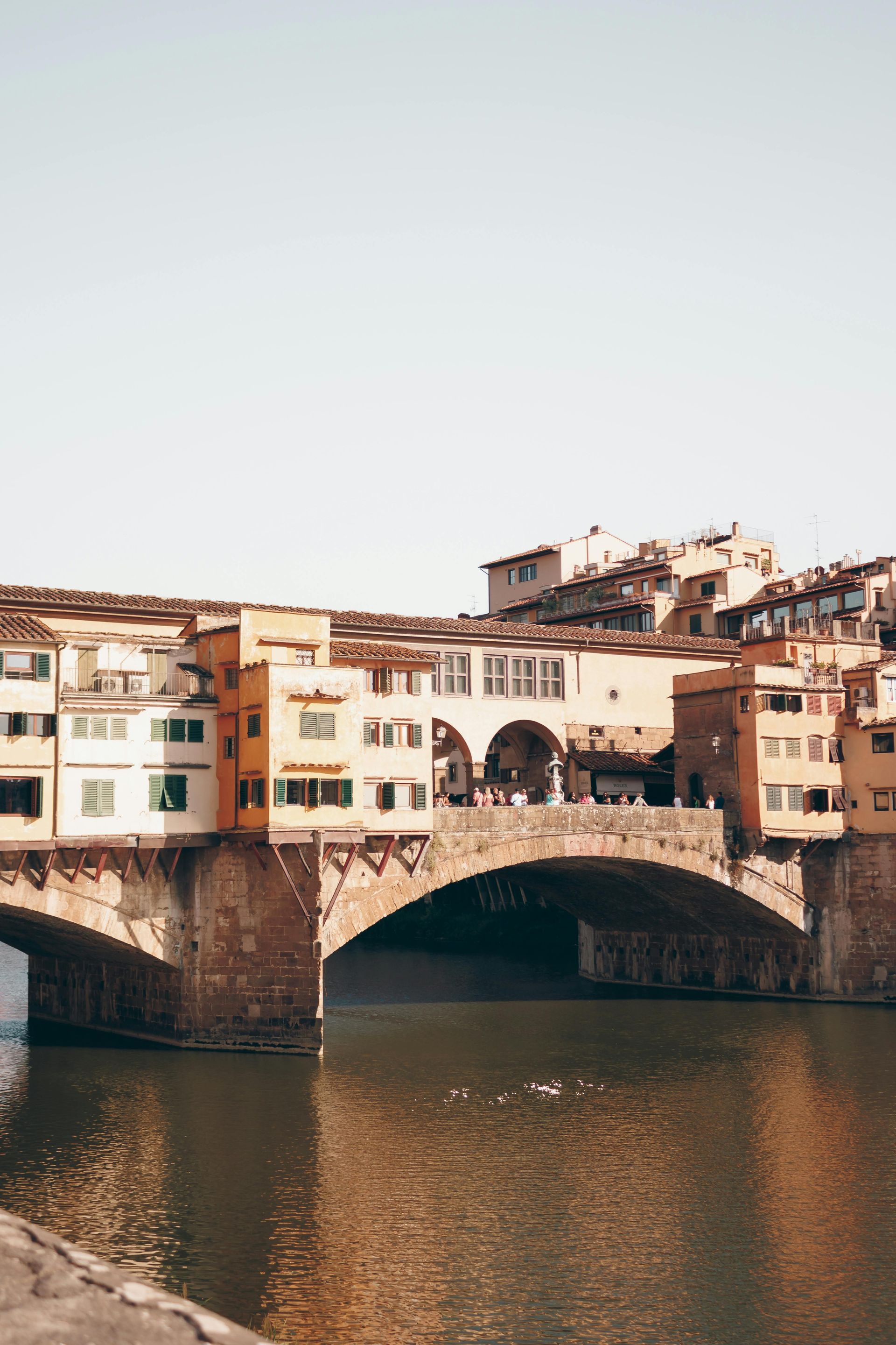 A bridge over a river with buildings in the background in Florence, Italy.